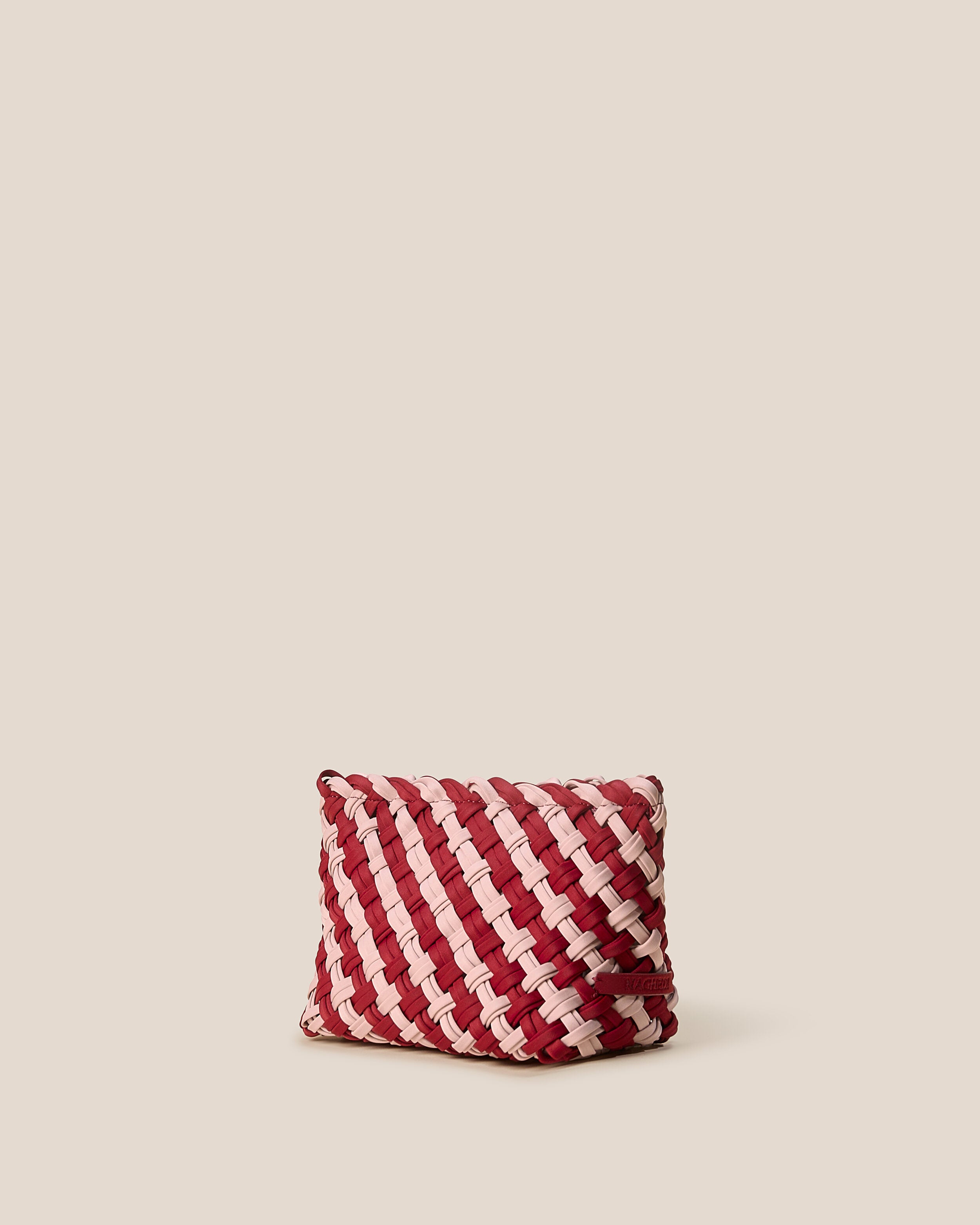 Gigi Clutch in Lychee shown from a side angle, highlighting its handwoven neoprene construction and top zip closure.