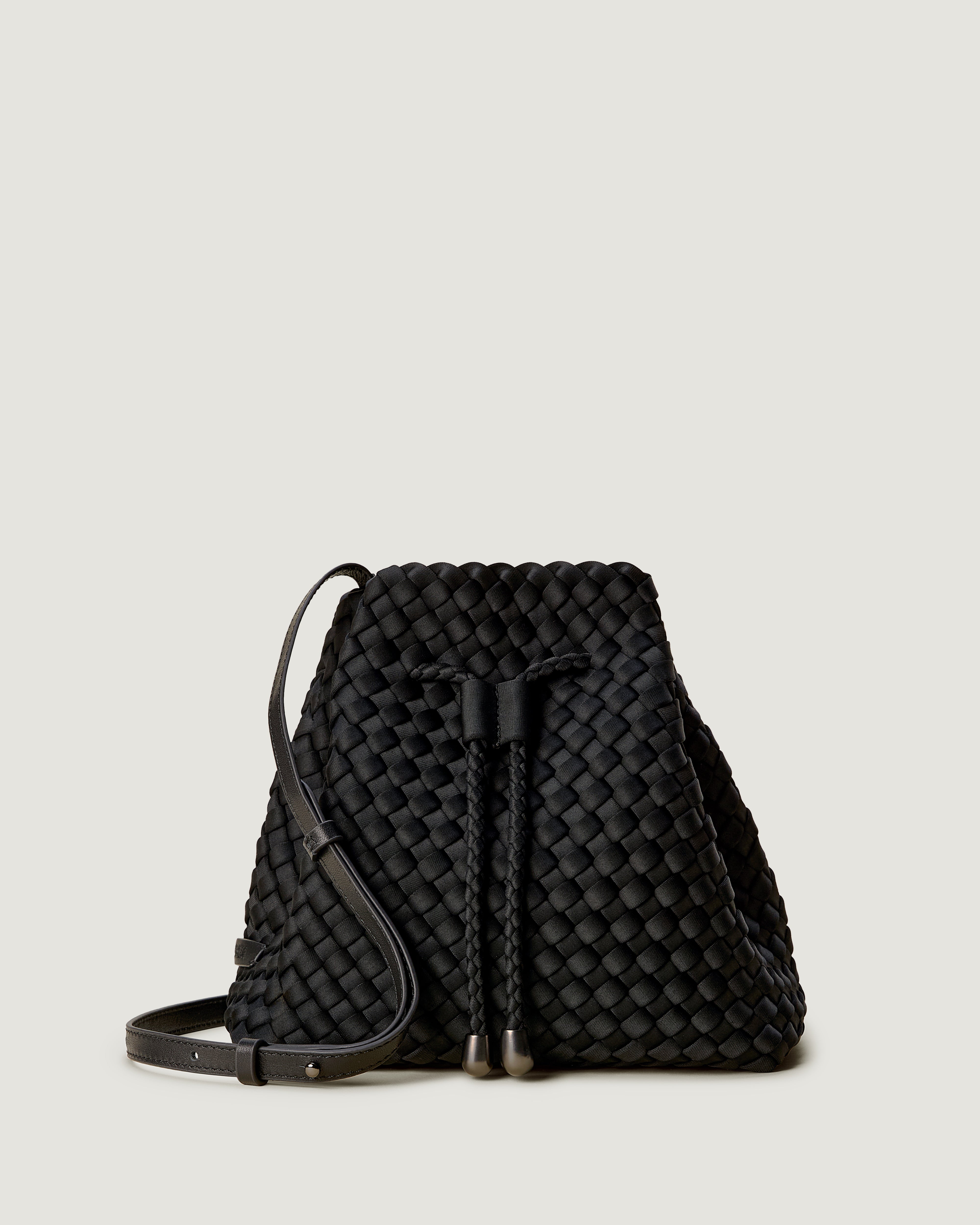 Gramercy Bucket in Onyx, a true black tone, in handwoven neoprene, featuring a drawstring closure, and adjustable leather crossbody strap.