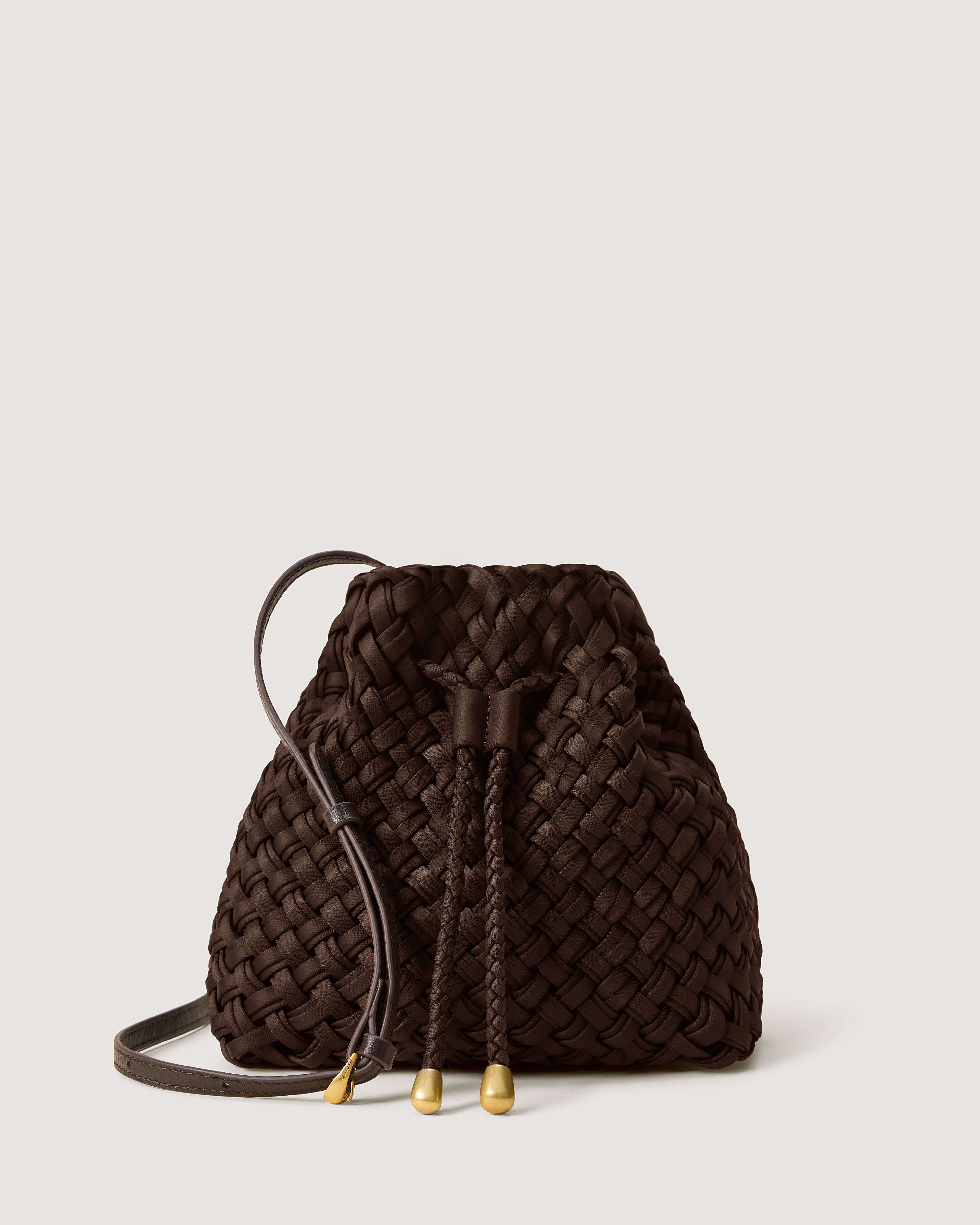 Gramercy Bucket in Chocolate, handwoven from doubled strands of rich dark brown neoprene. Featuring a drawstring closure, and adjustable leather crossbody strap.