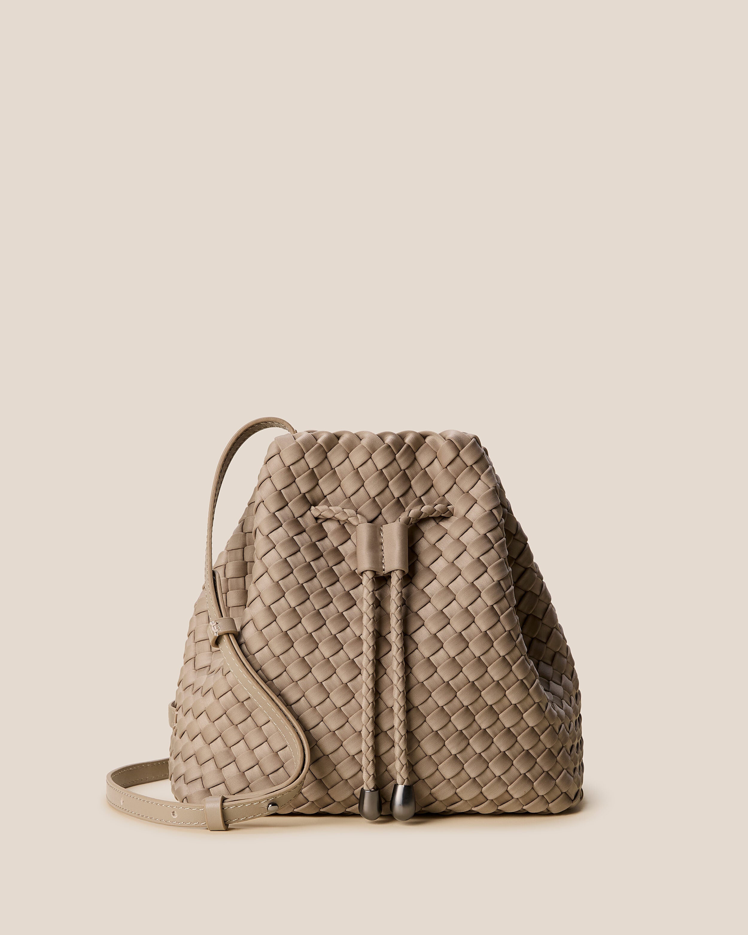 Gramercy Bucket in Cashmere, a taupe tone, in handwoven neoprene, featuring a drawstring closure, and adjustable leather crossbody strap.