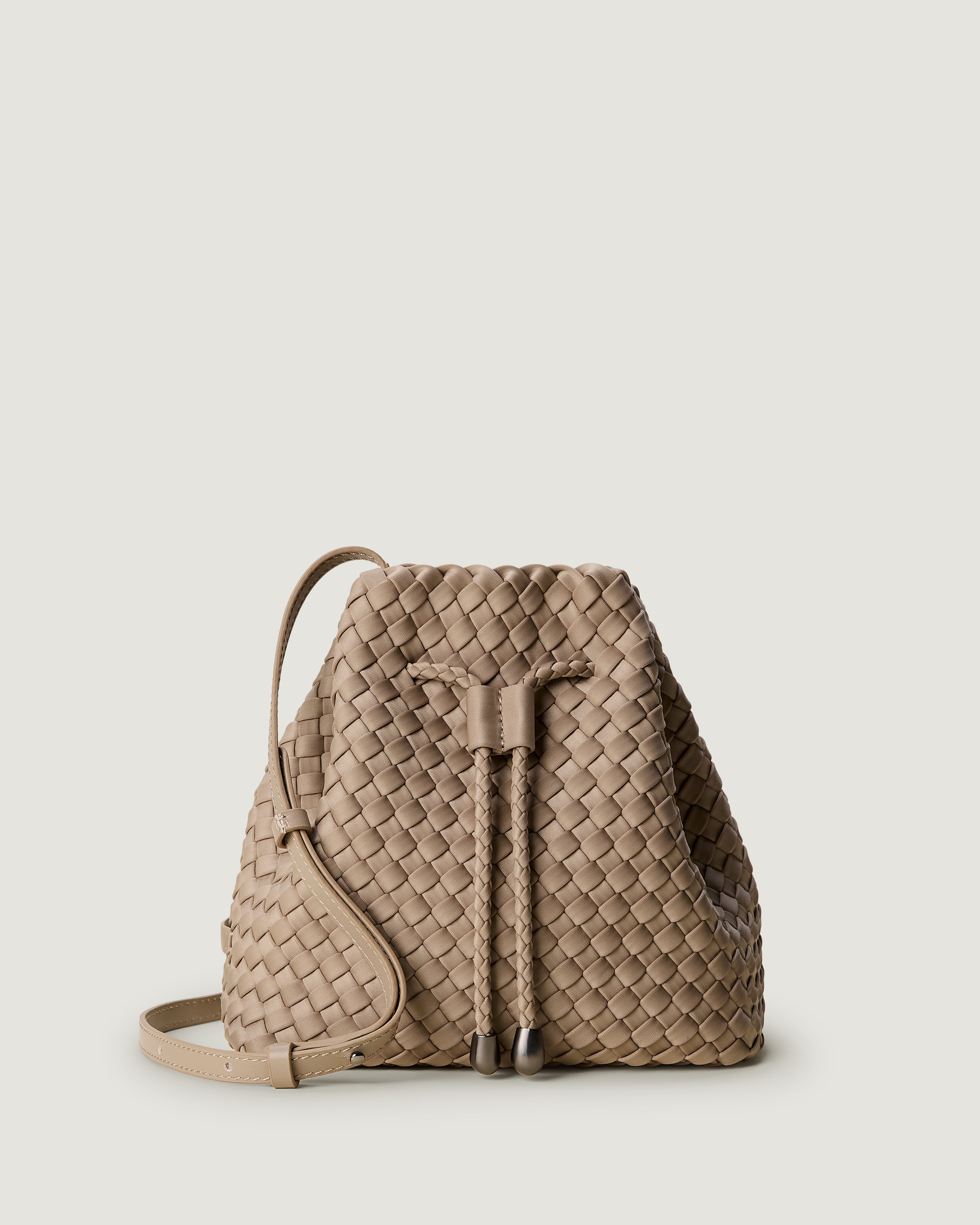 Gramercy Bucket in Cashmere, a taupe tone, in handwoven neoprene, featuring a drawstring closure, and adjustable leather crossbody strap.