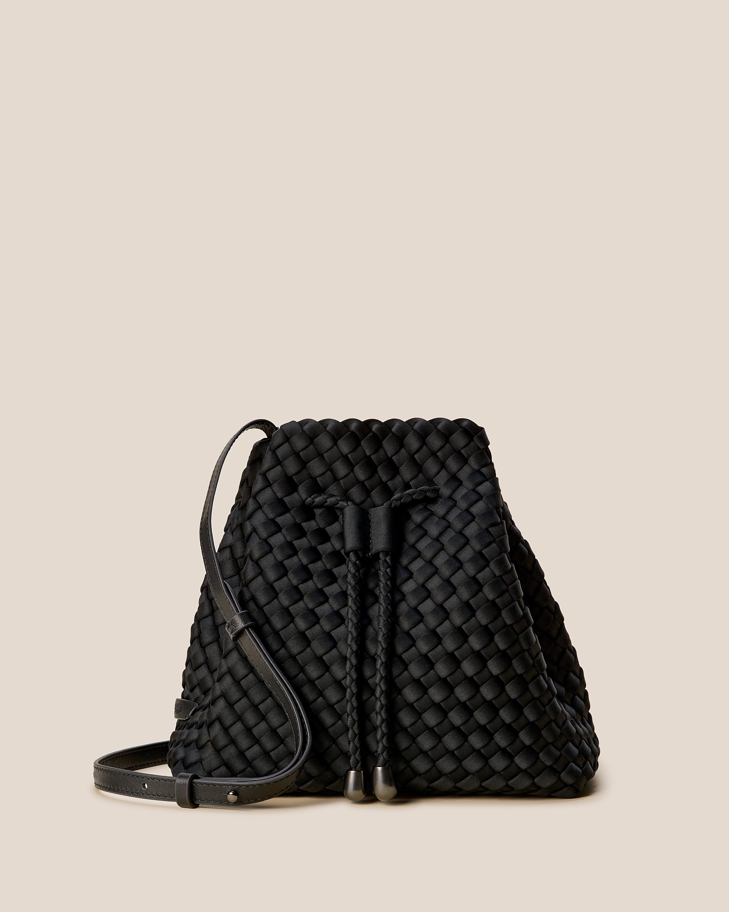 Gramercy Bucket in Onyx, a true black tone, in handwoven neoprene, featuring a drawstring closure, and adjustable leather crossbody strap.