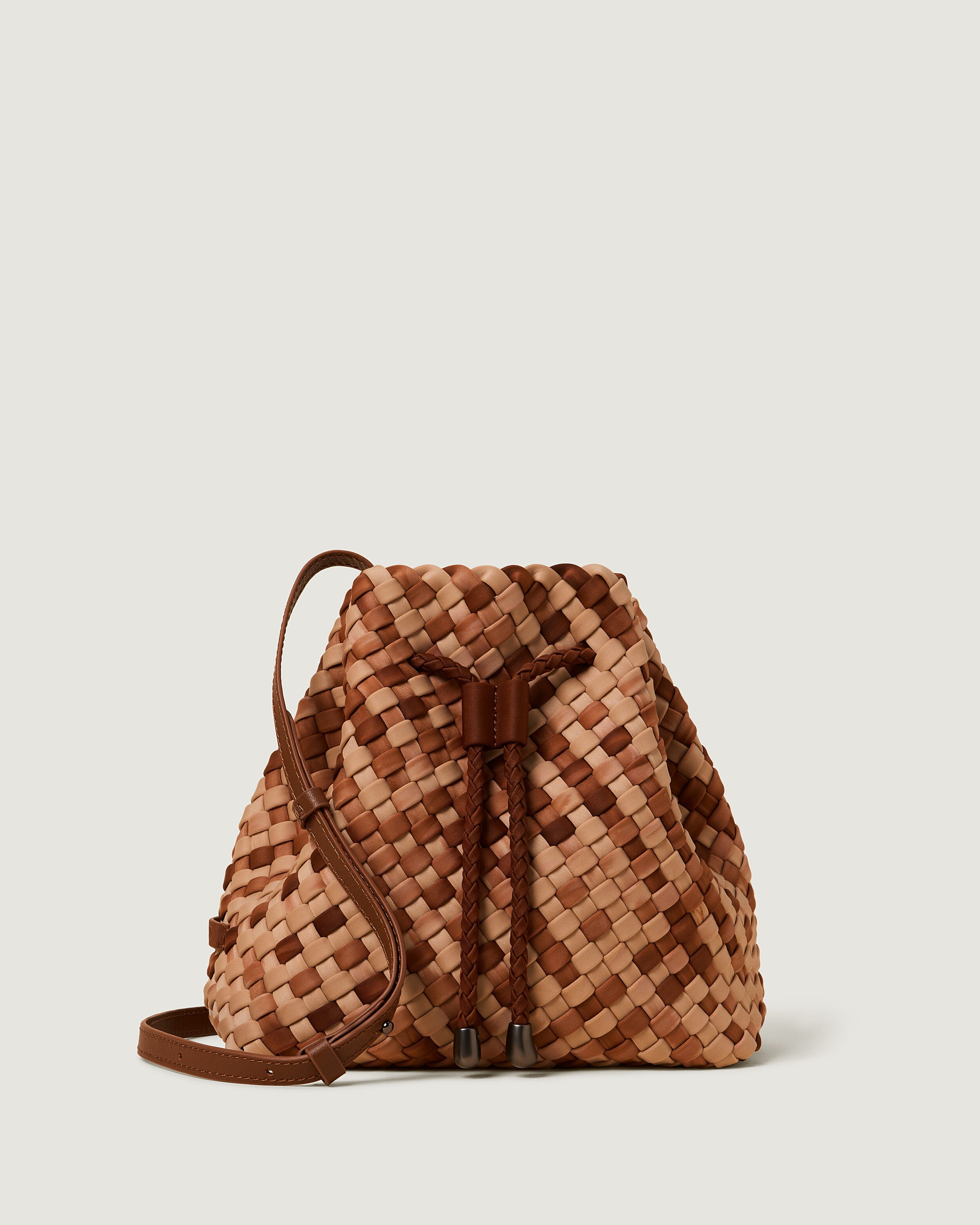 Gramercy Bucket in Fez, a camel brown and saddle brown tone, in handwoven neoprene, featuring a drawstring closure, and adjustable leather crossbody strap.