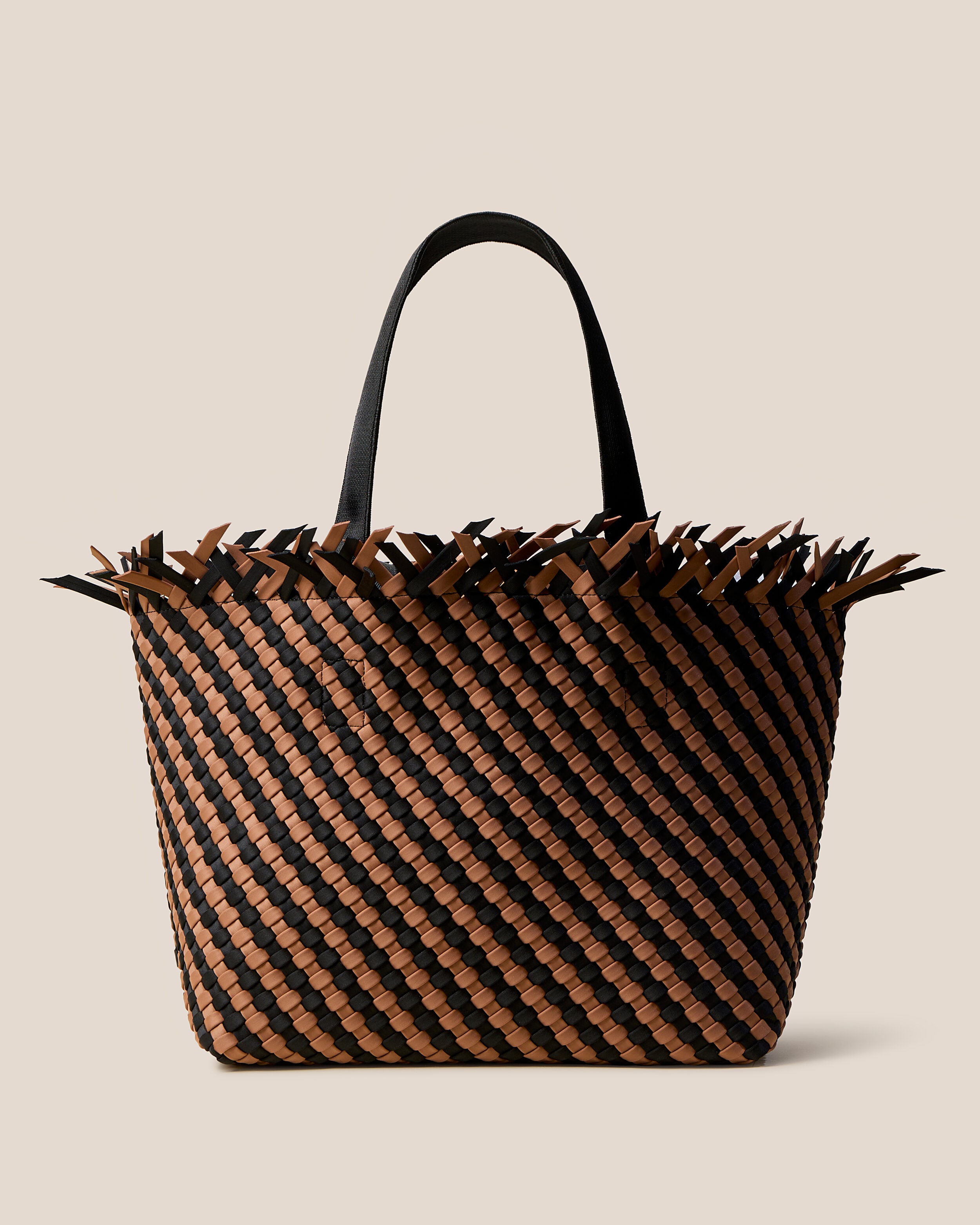 Havana  in Algarve, a mocha brown and true black tone, in handwoven neoprene, featuring an open top with magnetic snap closure, and sleek nylon webbing handles fit over the shoulder.