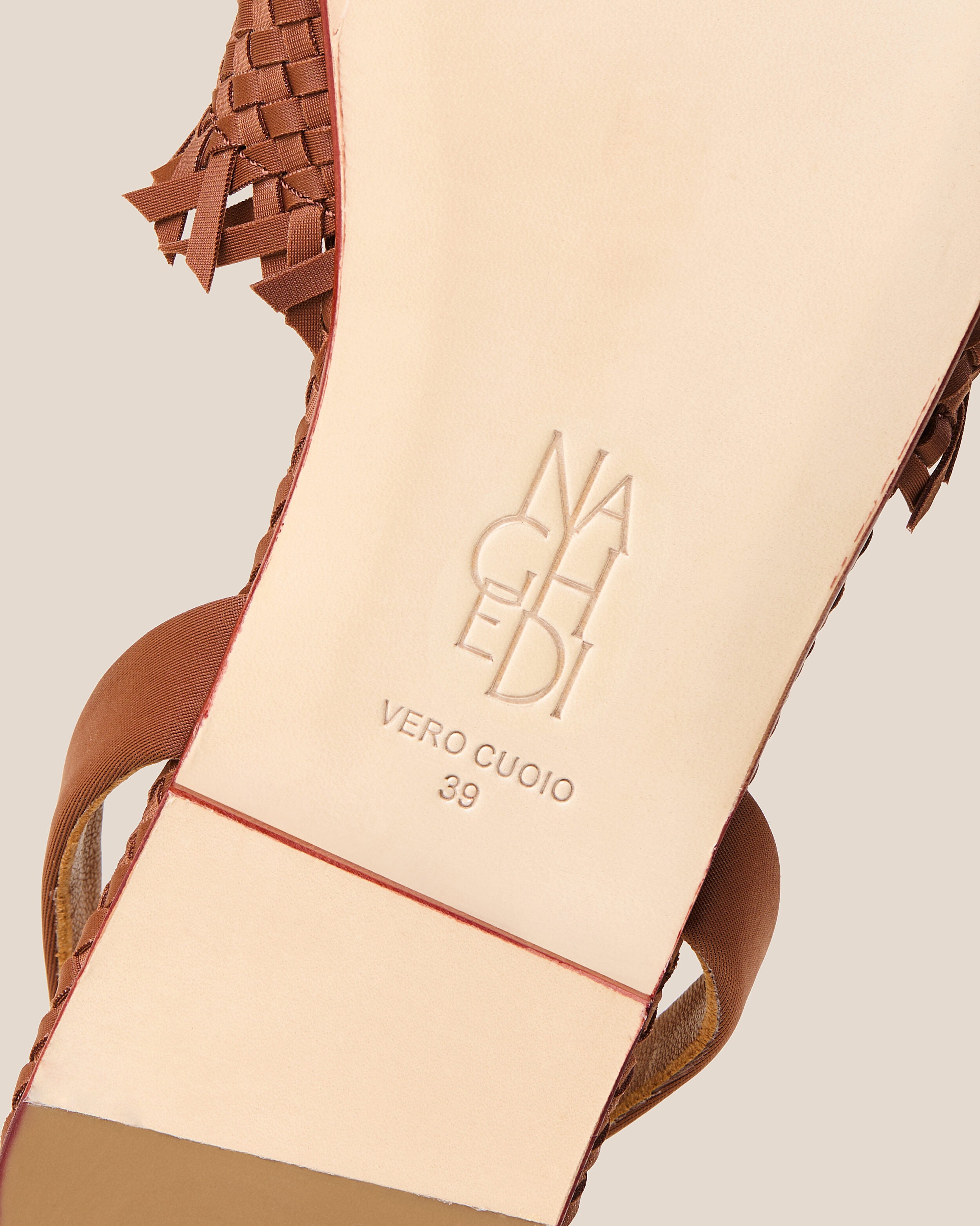 Shoe sole showing natural buffed leather sole, stamped NAGHEDI logo and size detail for The Havana Sandal in Adobe.