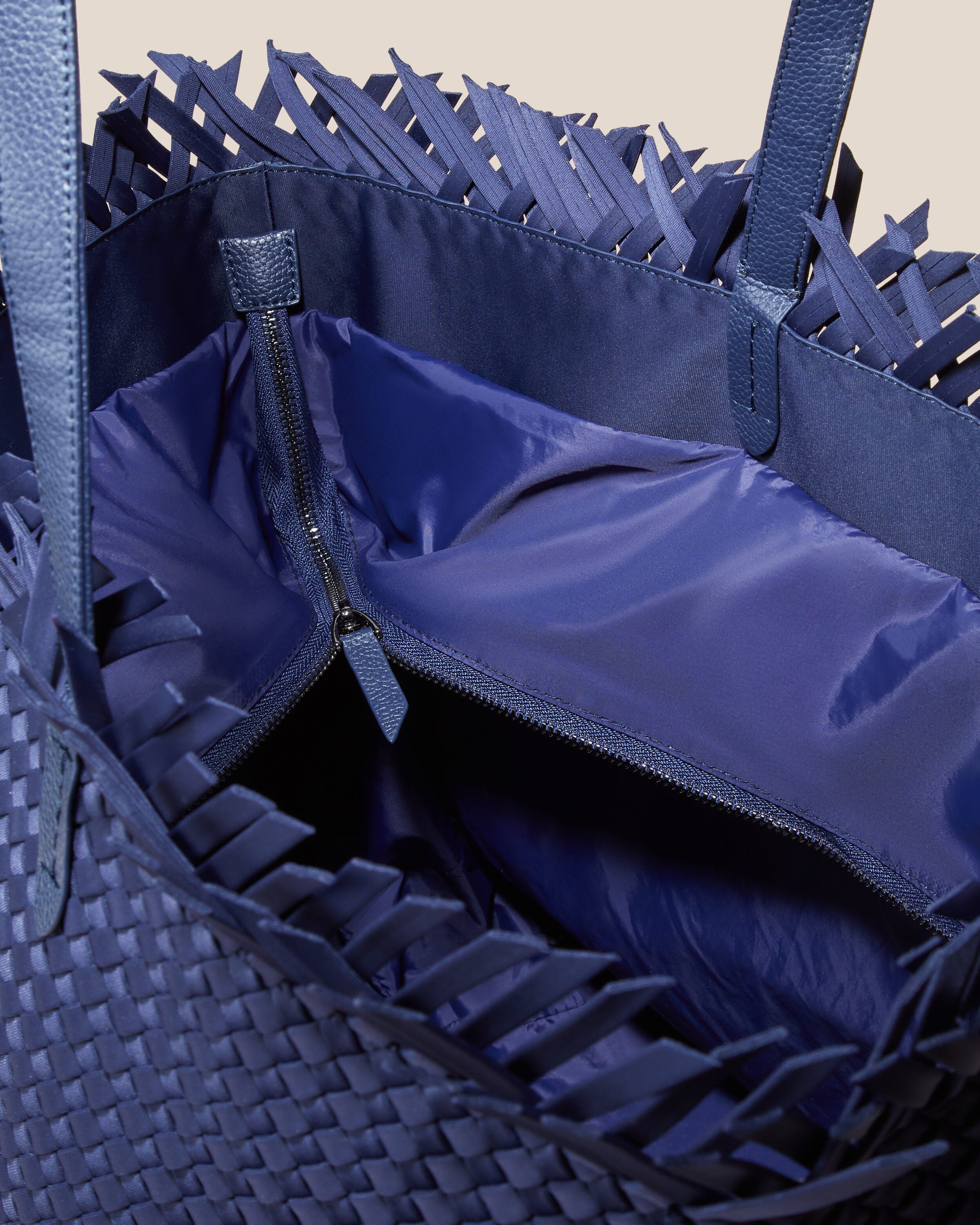 Interior close-up of Havana  in Ink Blue showing its top zip closure, interior pockets, and wipe-clean nylon interior.