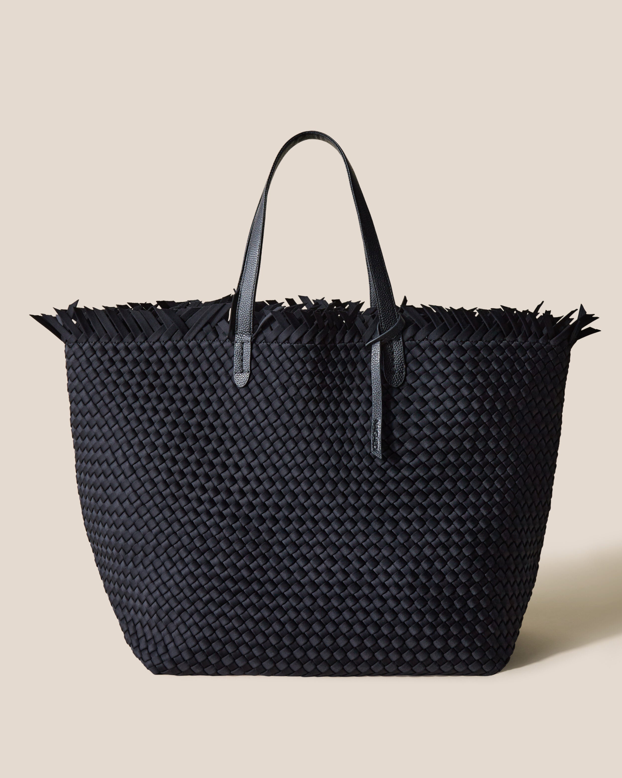 Havana  in Onyx, a true black tone, in handwoven neoprene, featuring a top zip closure, and sleek nylon webbing handles fit over the shoulder.