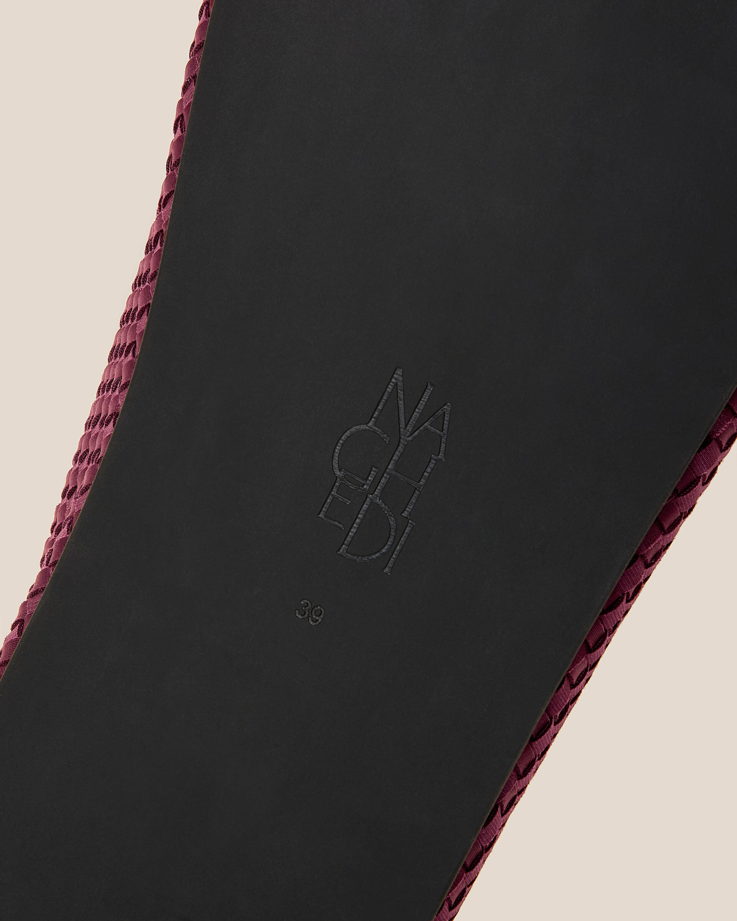 Shoe sole showing natural rubber sole, stamped NAGHEDI logo and size detail for The Hudson Clog in Bordeaux.