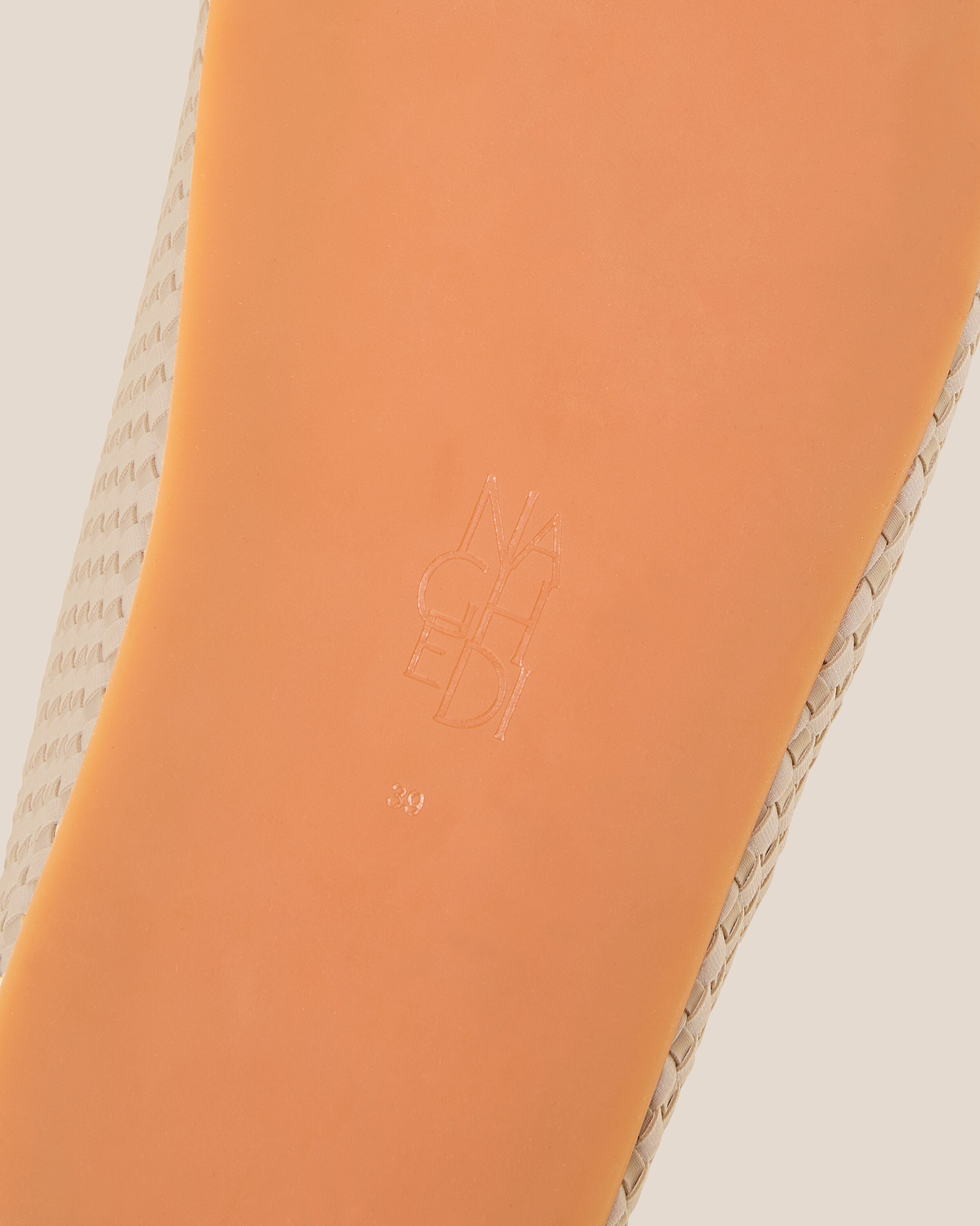 Shoe sole showing natural rubber sole, stamped NAGHEDI logo and size detail for The Hudson Clog in Ecru.