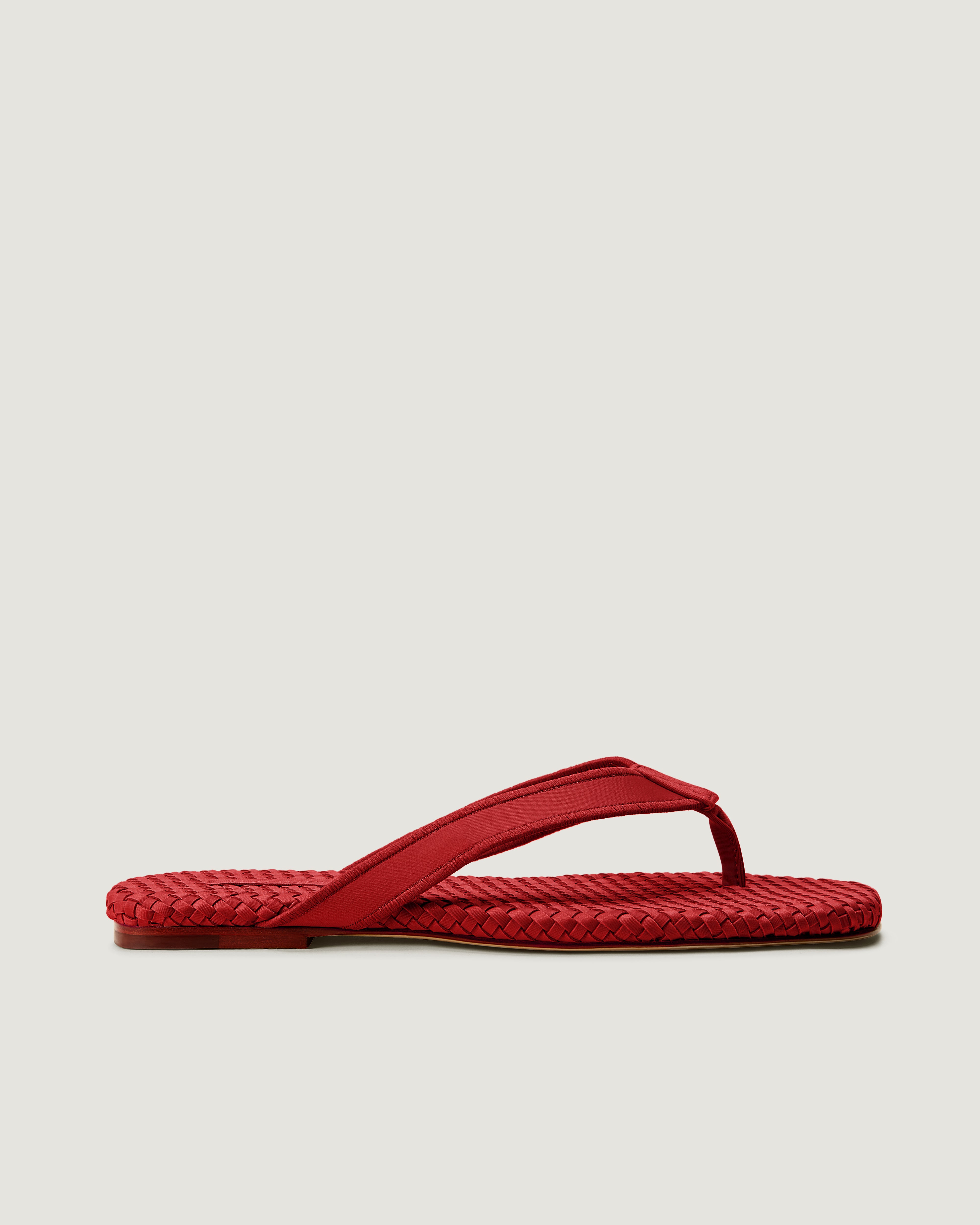 Side view of Hydra Flip Flop in Rosso, a rich red tone, featuring an thong toe and square silhouette.