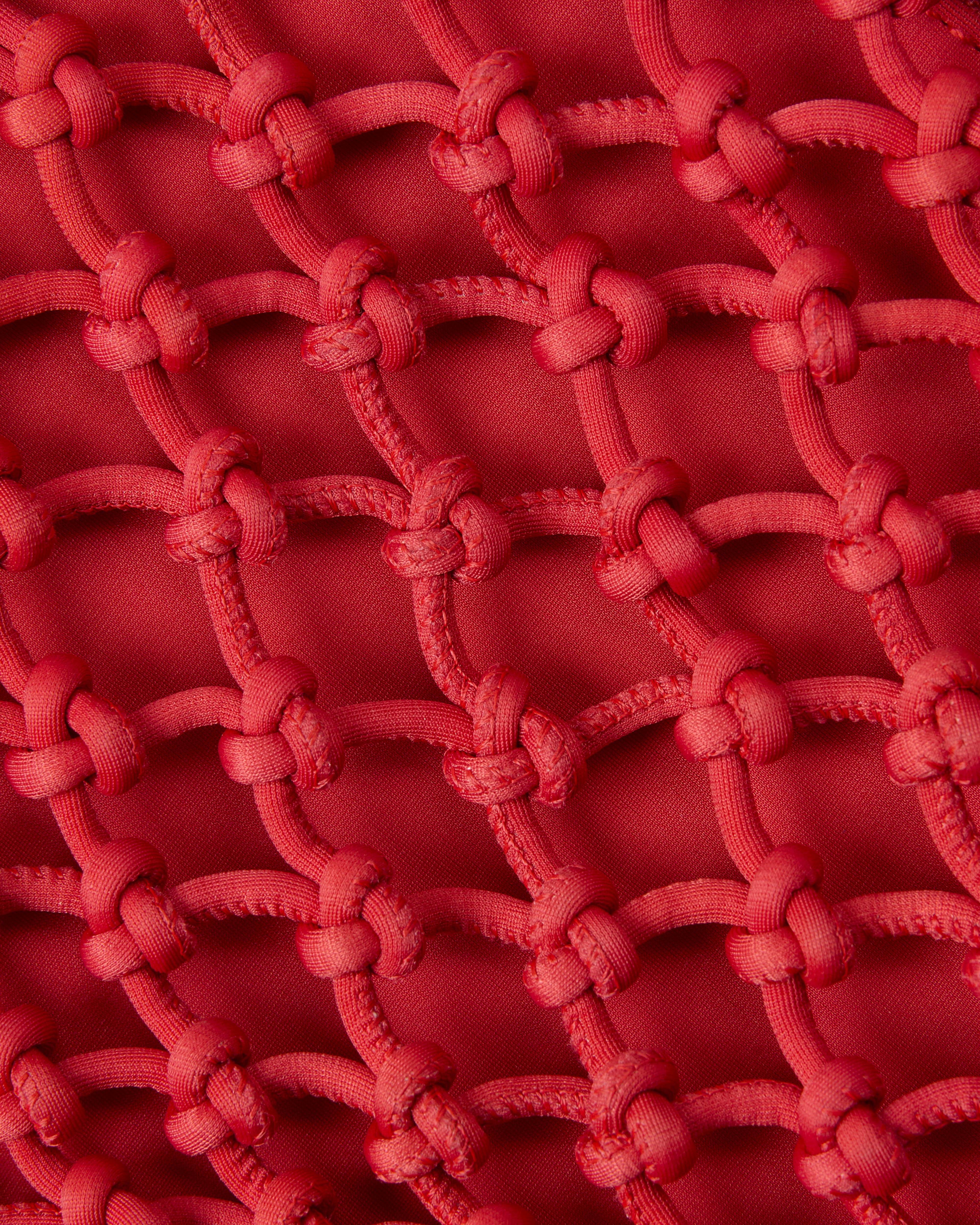 Close up of structure of woven neoprene net bag in cherry red