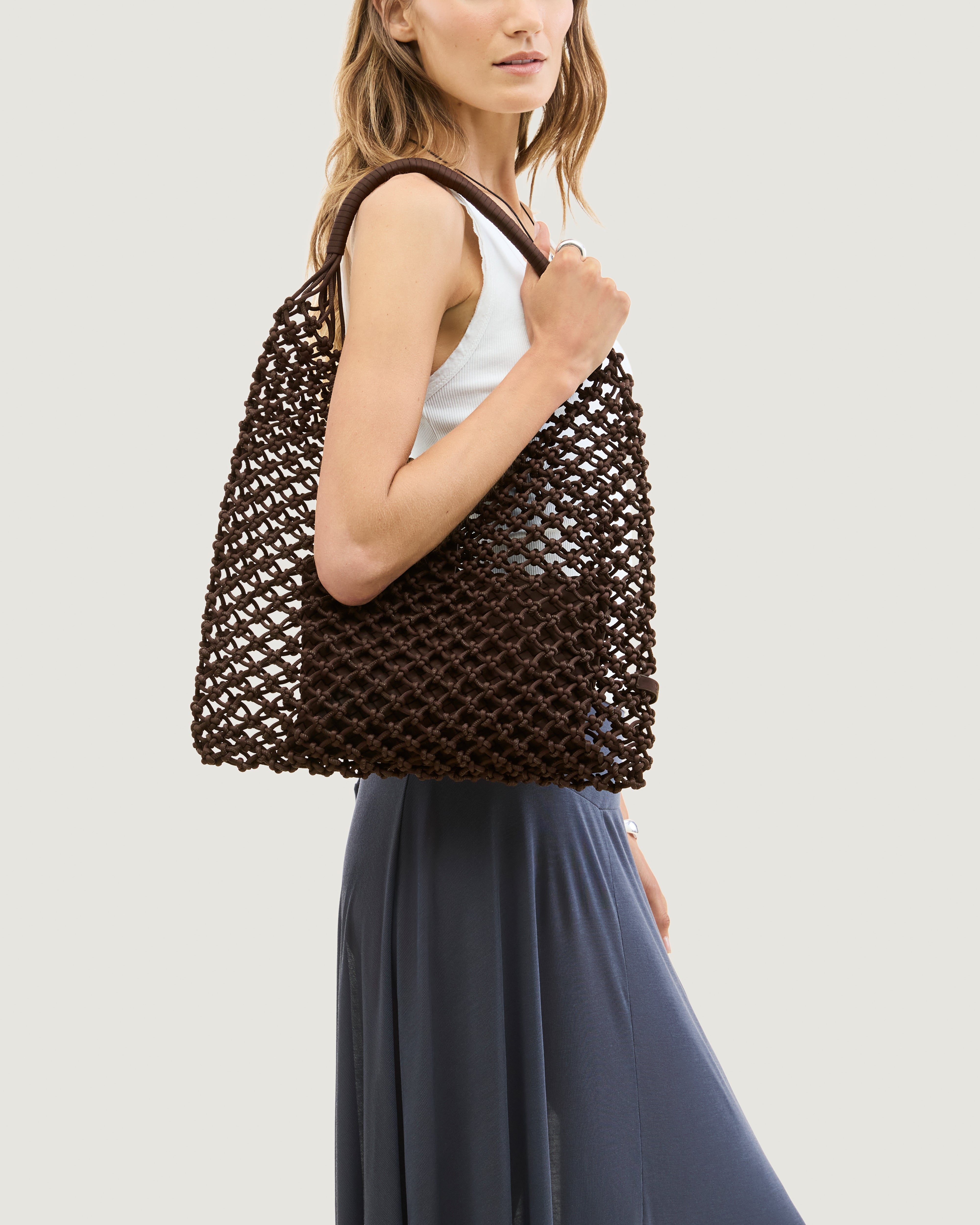 Model holding woven neoprene net bag in chocolate brown over her shoulder