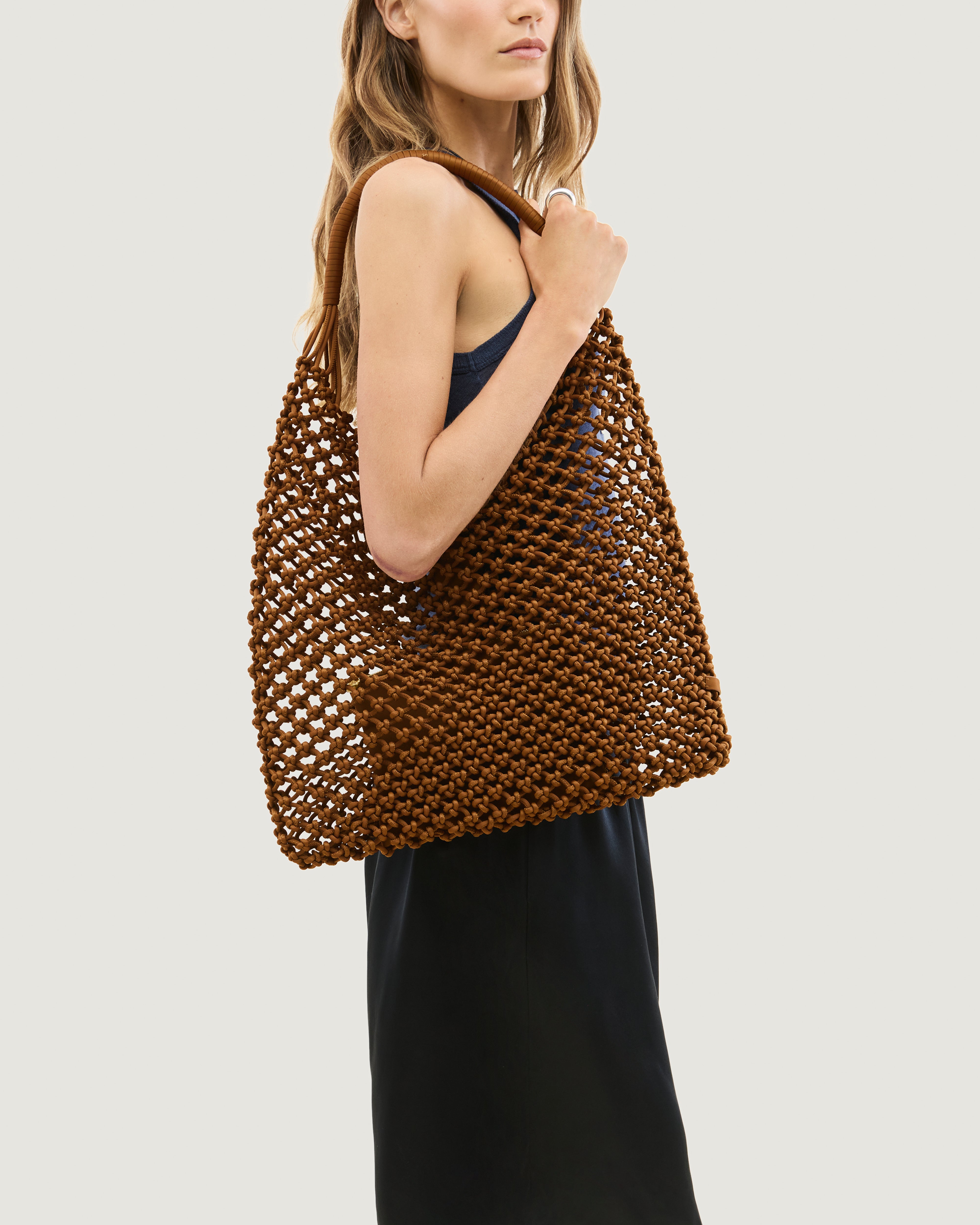 Model holding neoprene woven net bag in saddle brown over her shoulder