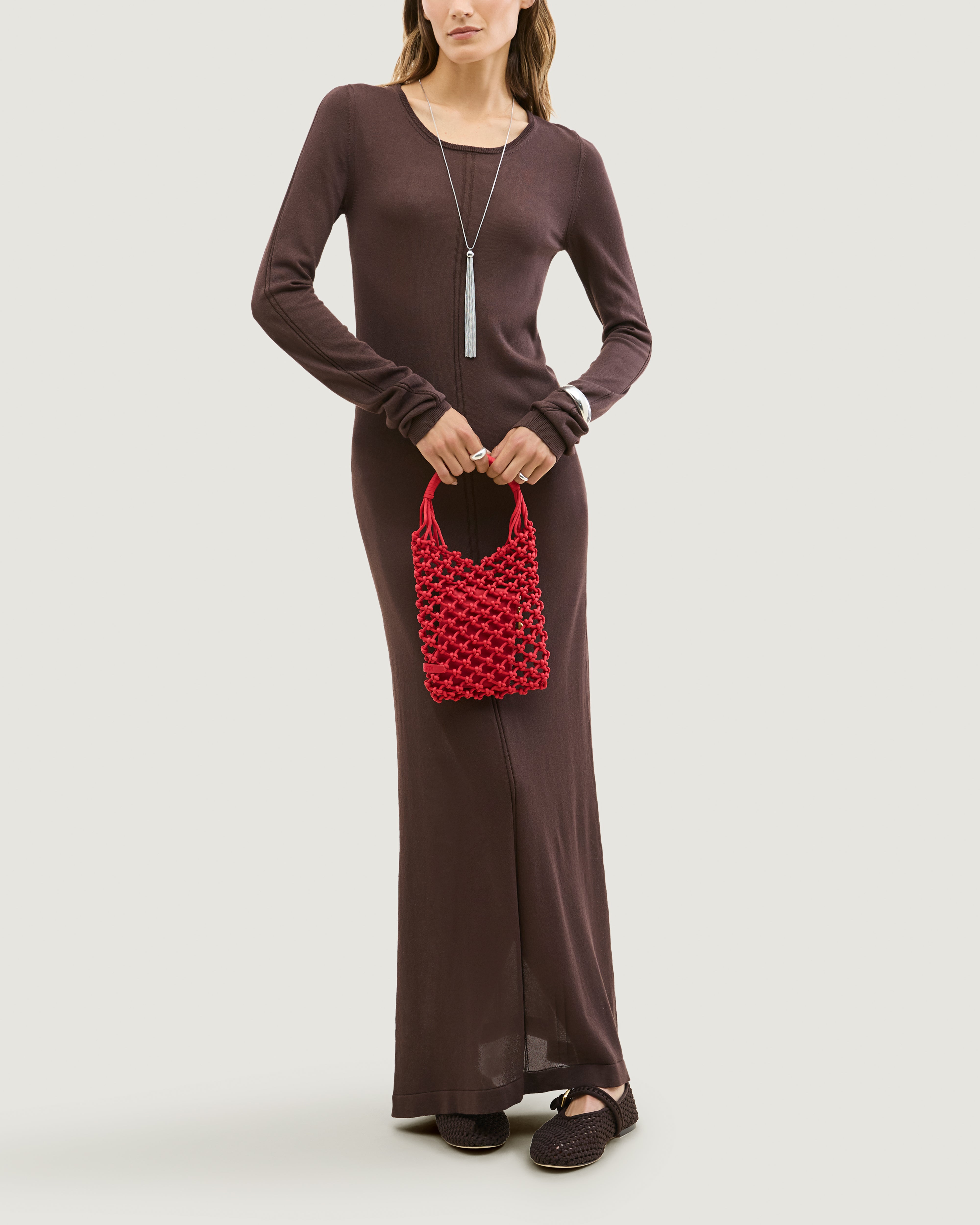 Model holding woven neoprene net bag in cherry red in front of her body