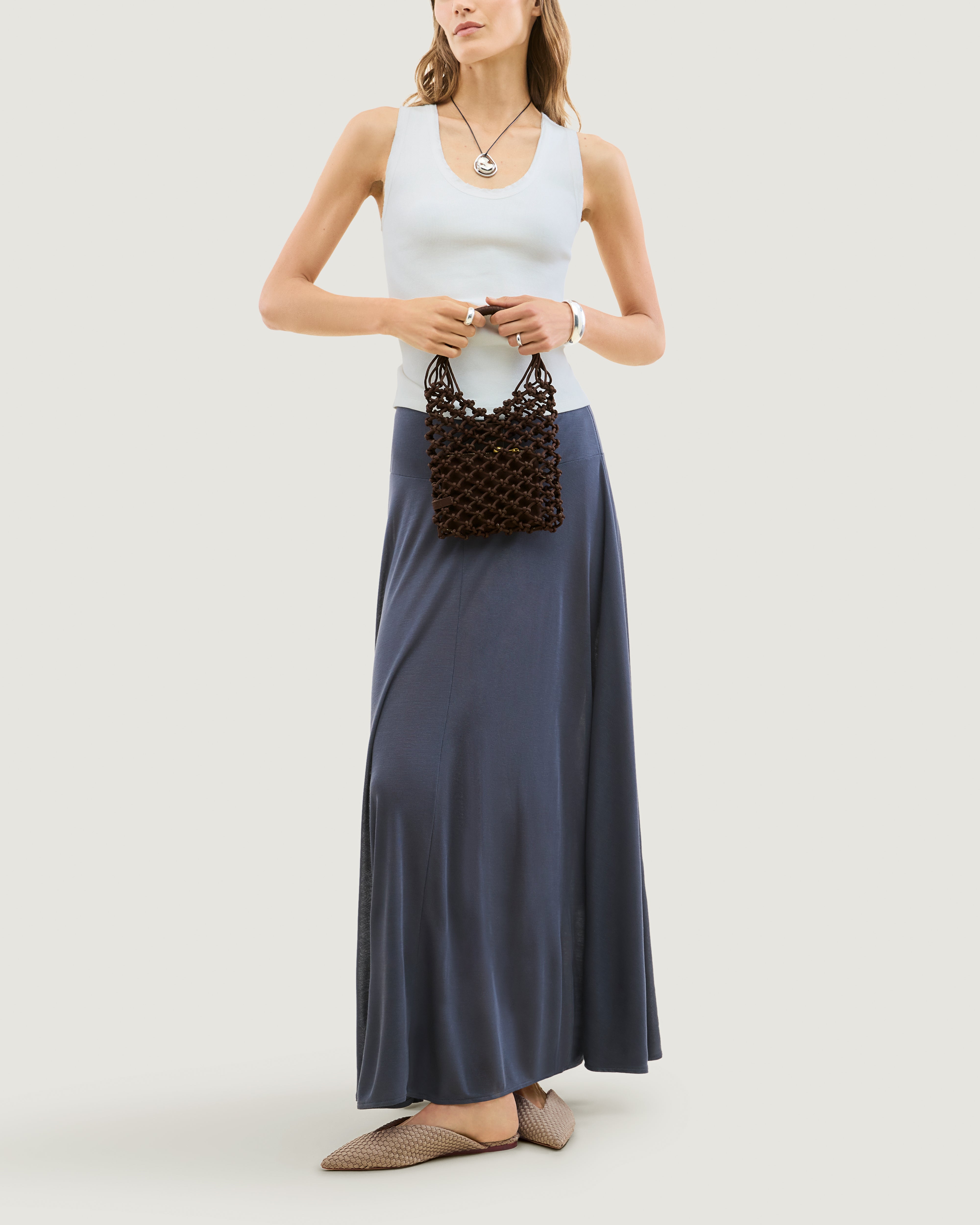 Model holding woven neoprene net bag in chocolate brown in front of her body