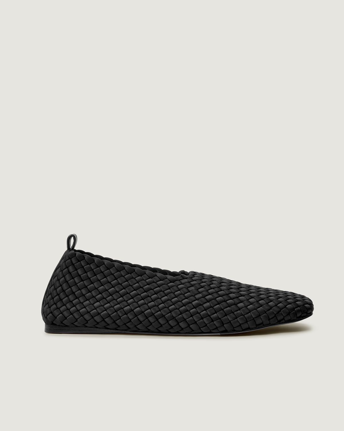 Side view of Jeju Glove Flat in Onyx, a true black tone, featuring a closed toe and round silhouette, featuring an adjustable strap with buckle closure.