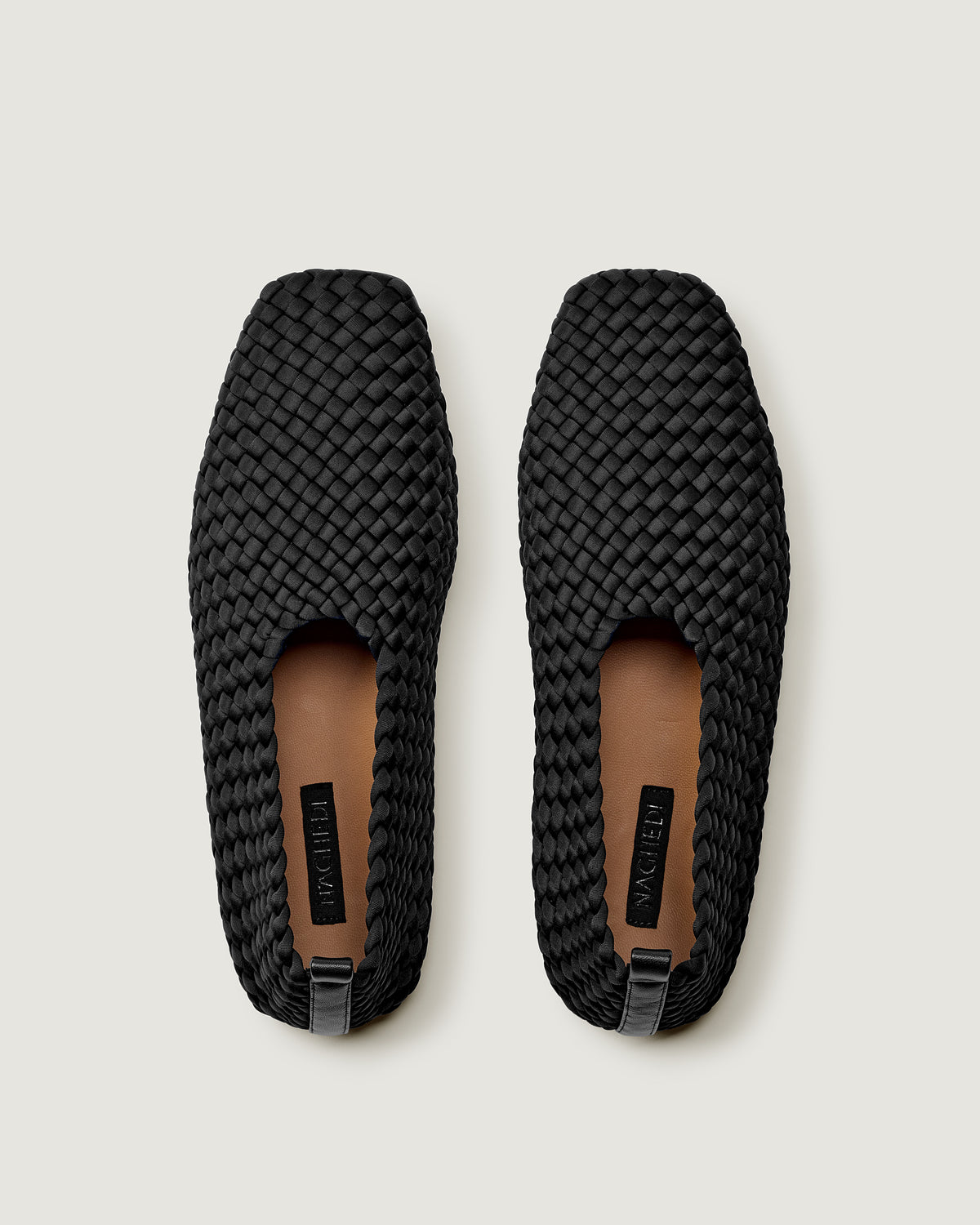 Top view of pair of The Jeju Glove Flat in Onyx showing the natural tanned leather insole