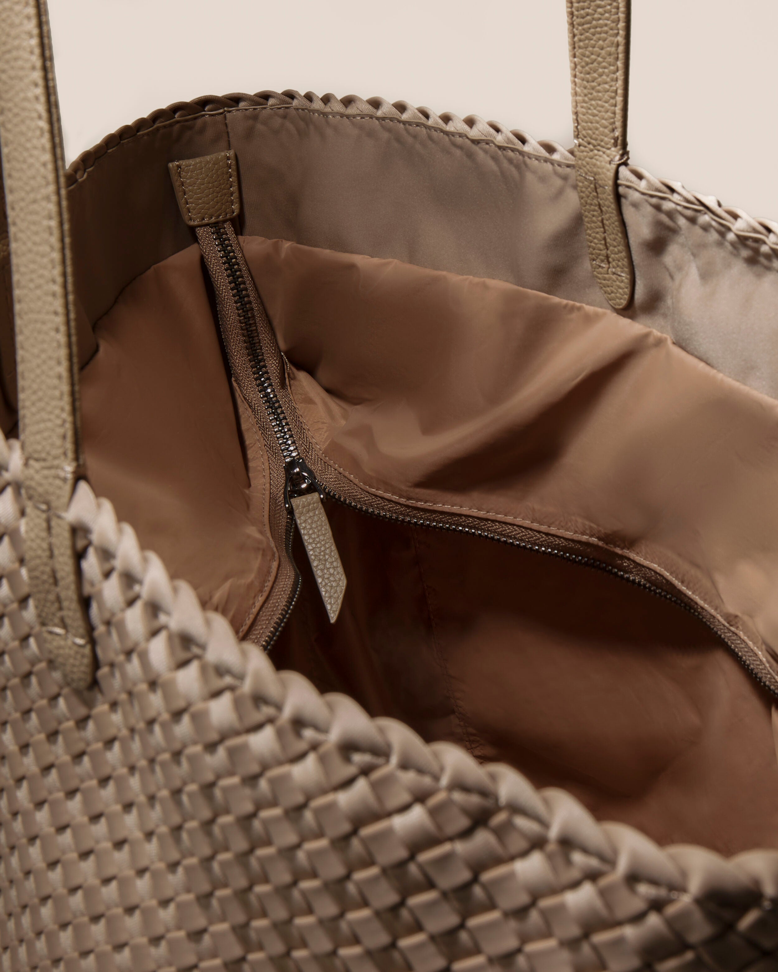 Interior close-up of Jetsetter Tote in Cashmere showing its top zip closure, interior pockets, and wipe-clean nylon interior.