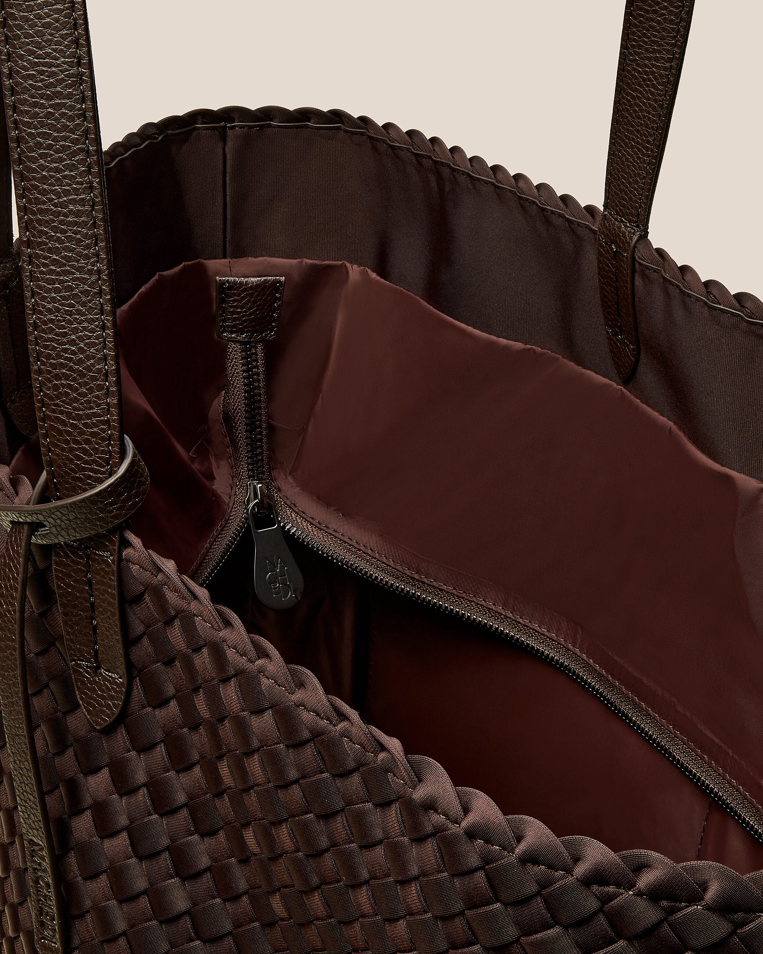 Interior close-up of Jetsetter Tote in Chocolate showing its top zip closure, interior pockets, and wipe-clean nylon interior.