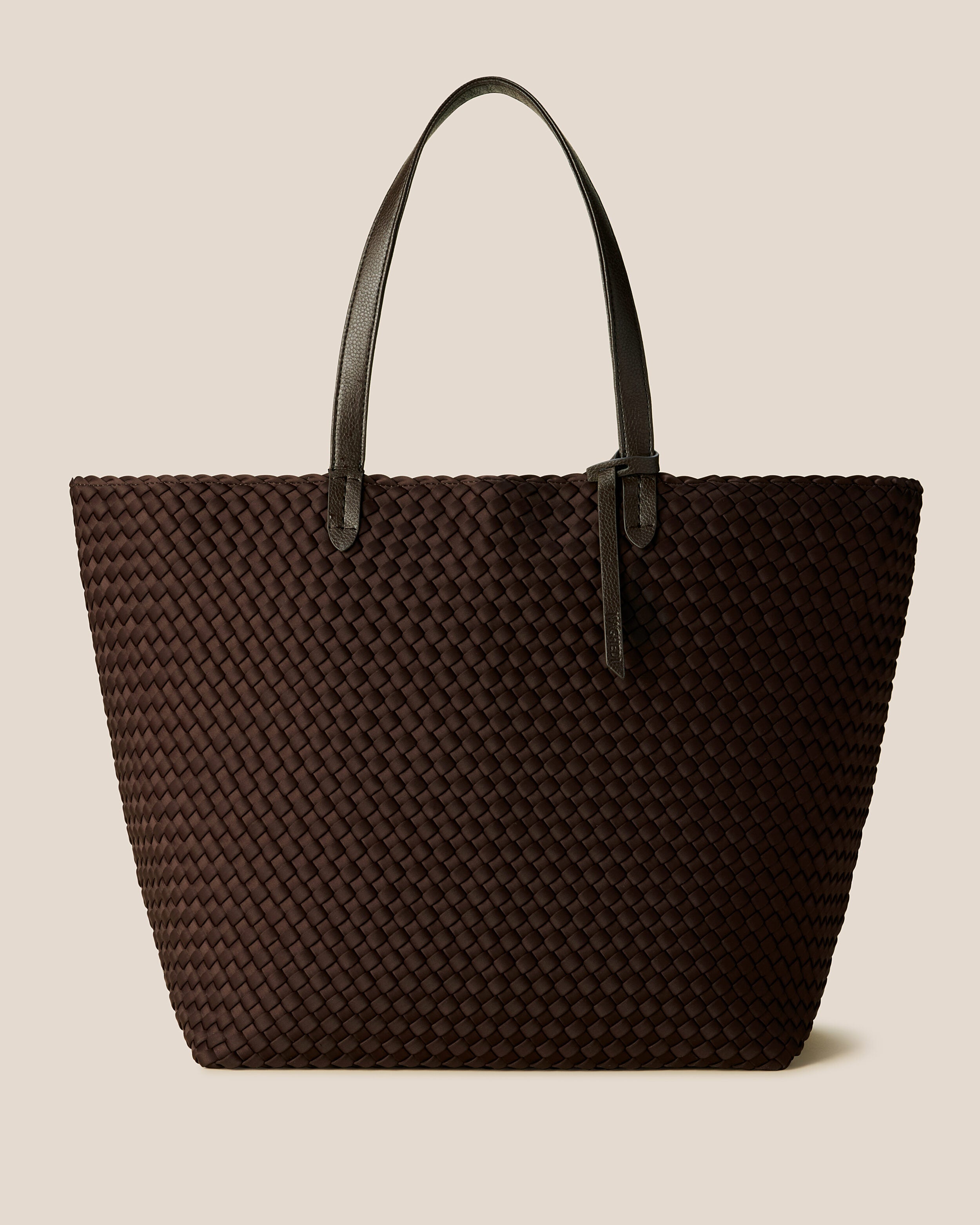Jetsetter Tote in Chocolate, a dark chocolate brown tone, in handwoven neoprene, featuring a top zip closure, and vegan leather handles.