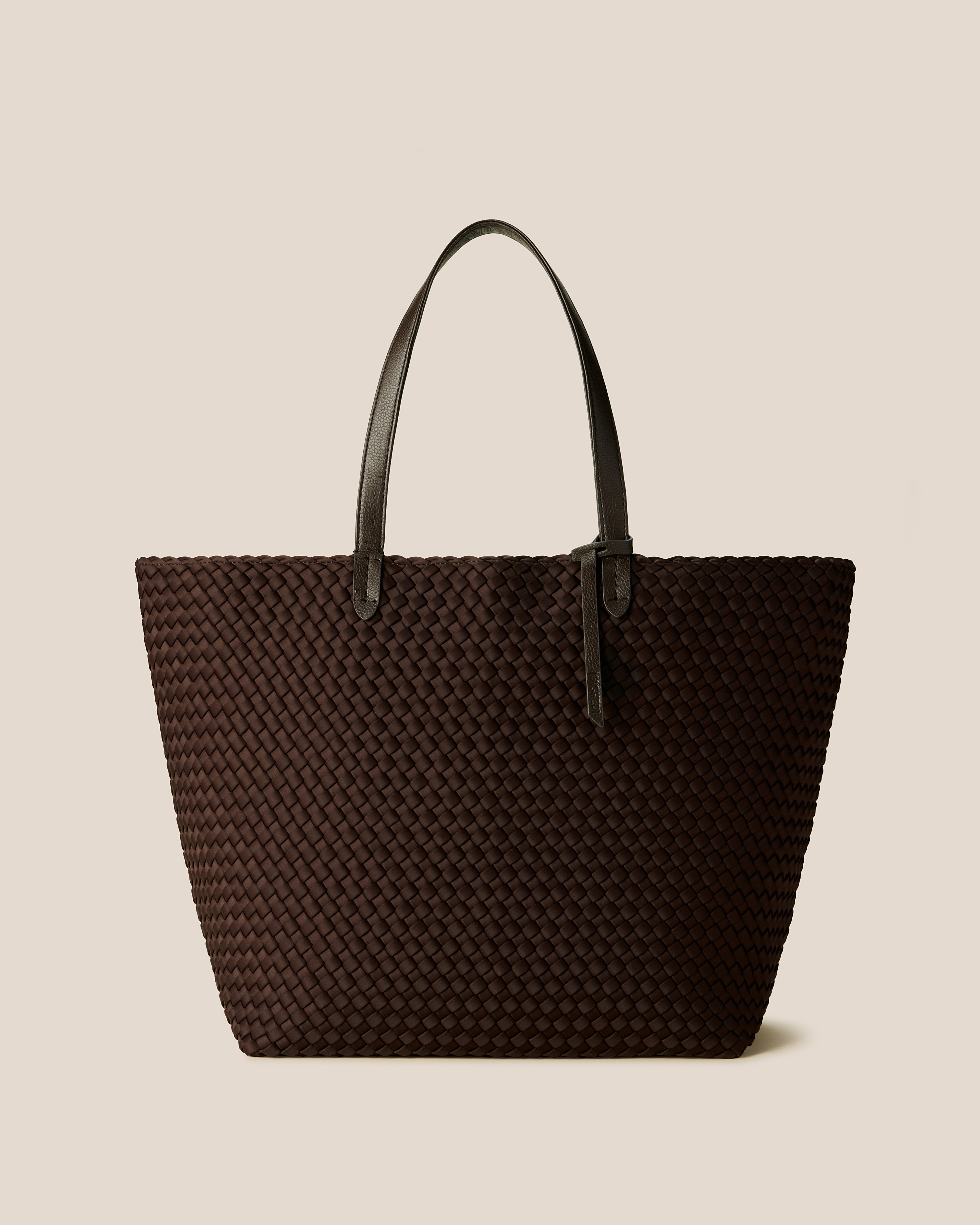 Jetsetter Tote in Chocolate, a dark chocolate brown tone, in handwoven neoprene, featuring a top zip closure, and vegan leather handles.