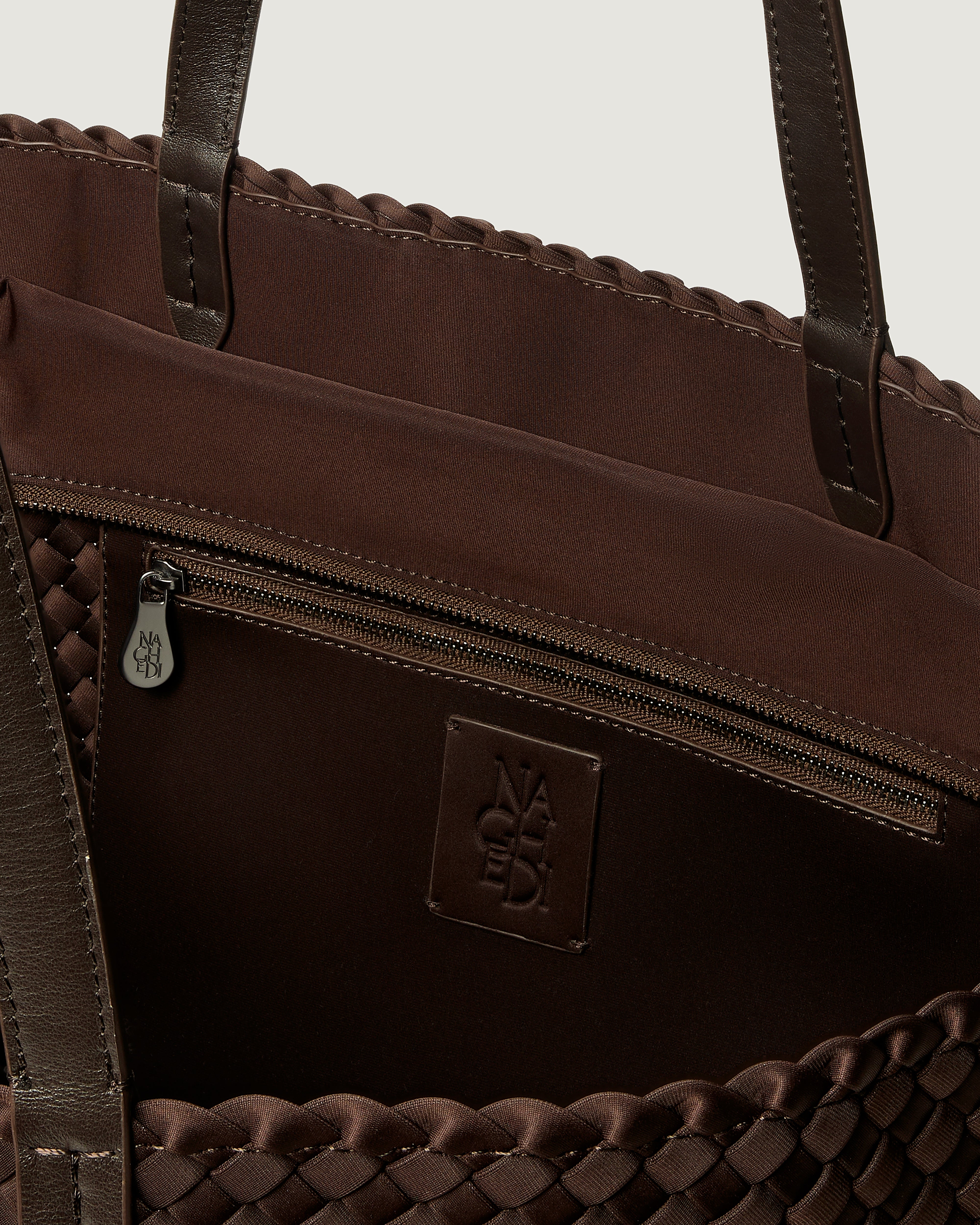 Interior close-up of Jetsetter Tote in Chocolate showing its top zip closure, interior pocket, and unlined interior.