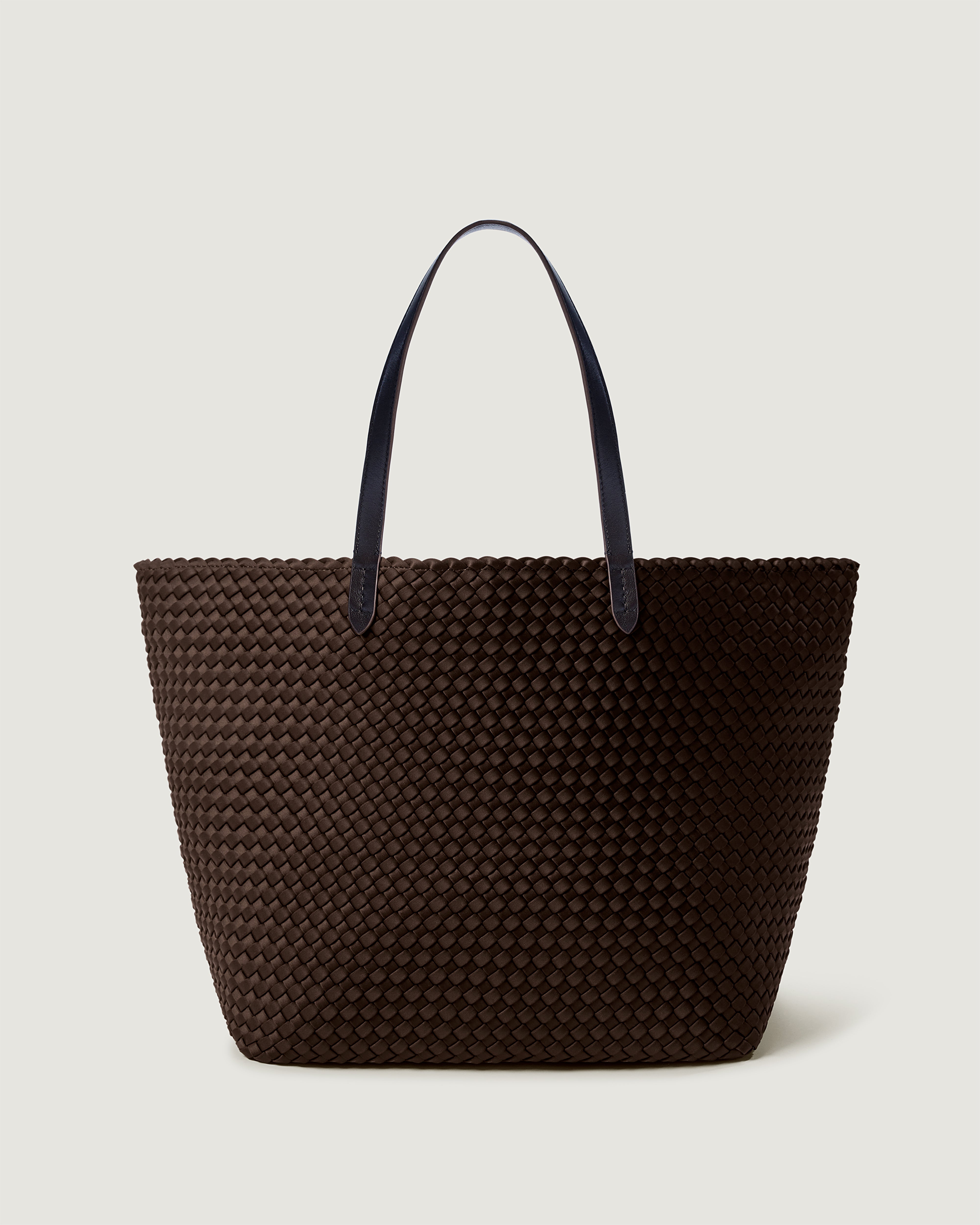 Jetsetter Tote in Chocolate, a dark chocolate brown tone, in handwoven neoprene, featuring a top zip closure, and  leather handles.