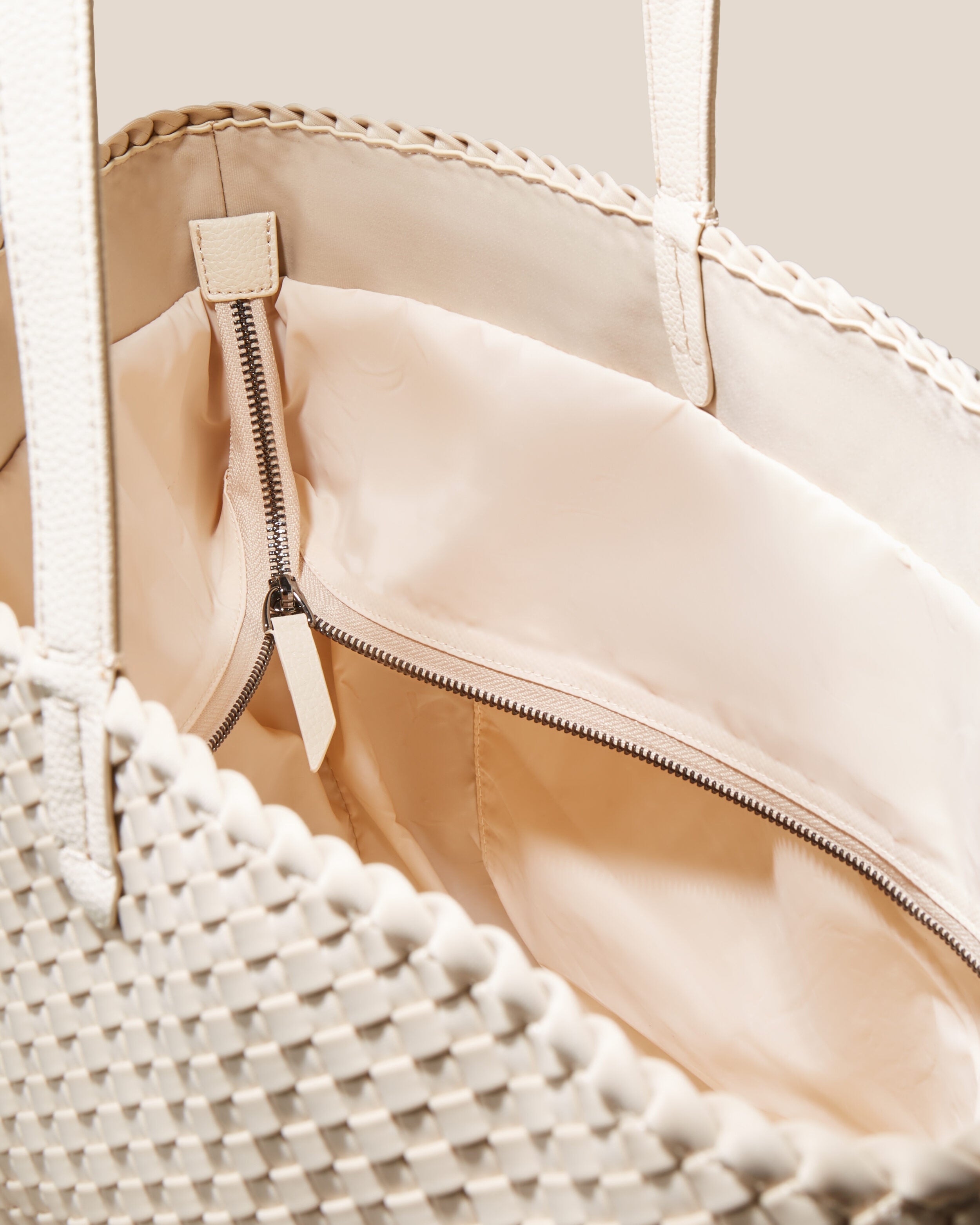 Interior close-up of Jetsetter Tote in Ecru showing its top zip closure, interior pockets, and wipe-clean nylon interior.