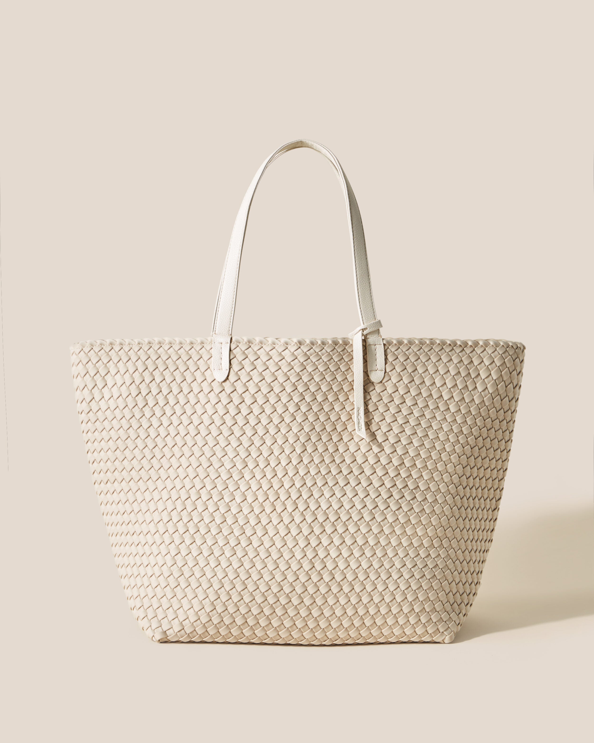 Jetsetter Tote in Ecru, a cream tone, in handwoven neoprene, featuring a top zip closure, and vegan leather handles.
