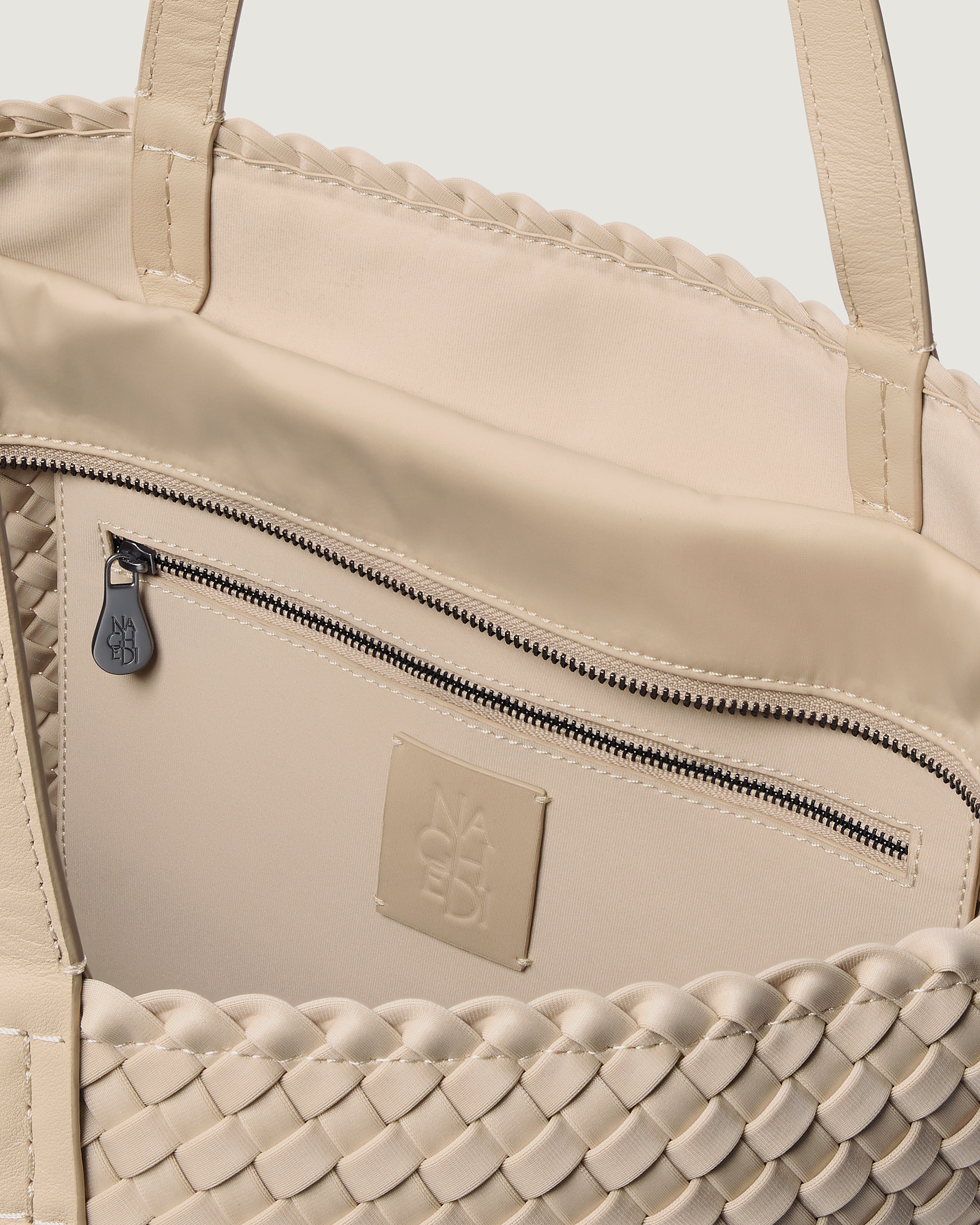 Interior close-up of Jetsetter Tote in Ecru showing its top zip closure, interior pocket, and unlined interior.