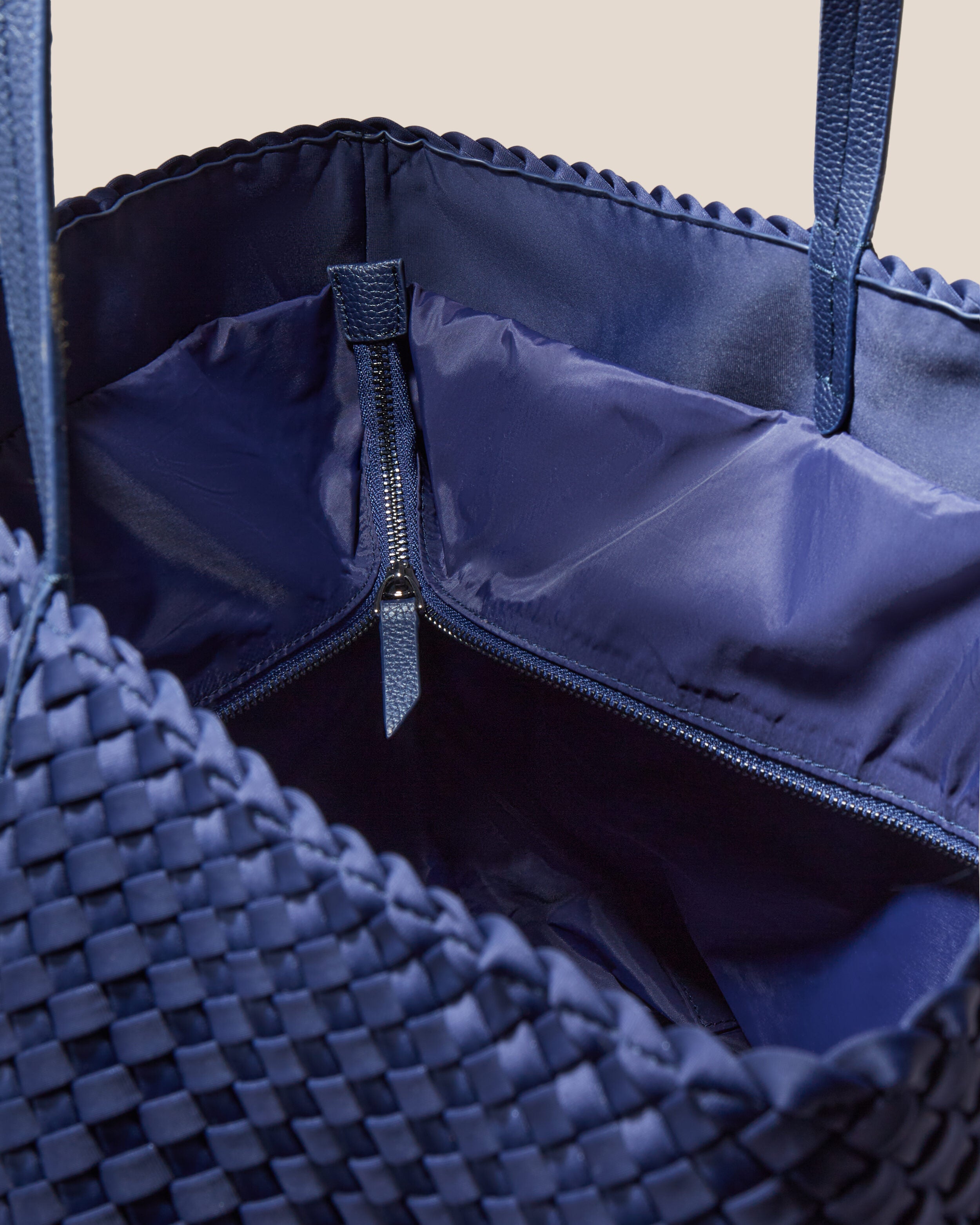 Interior close-up of Jetsetter Tote in Ink Blue showing its top zip closure, interior pockets, and wipe-clean nylon interior.