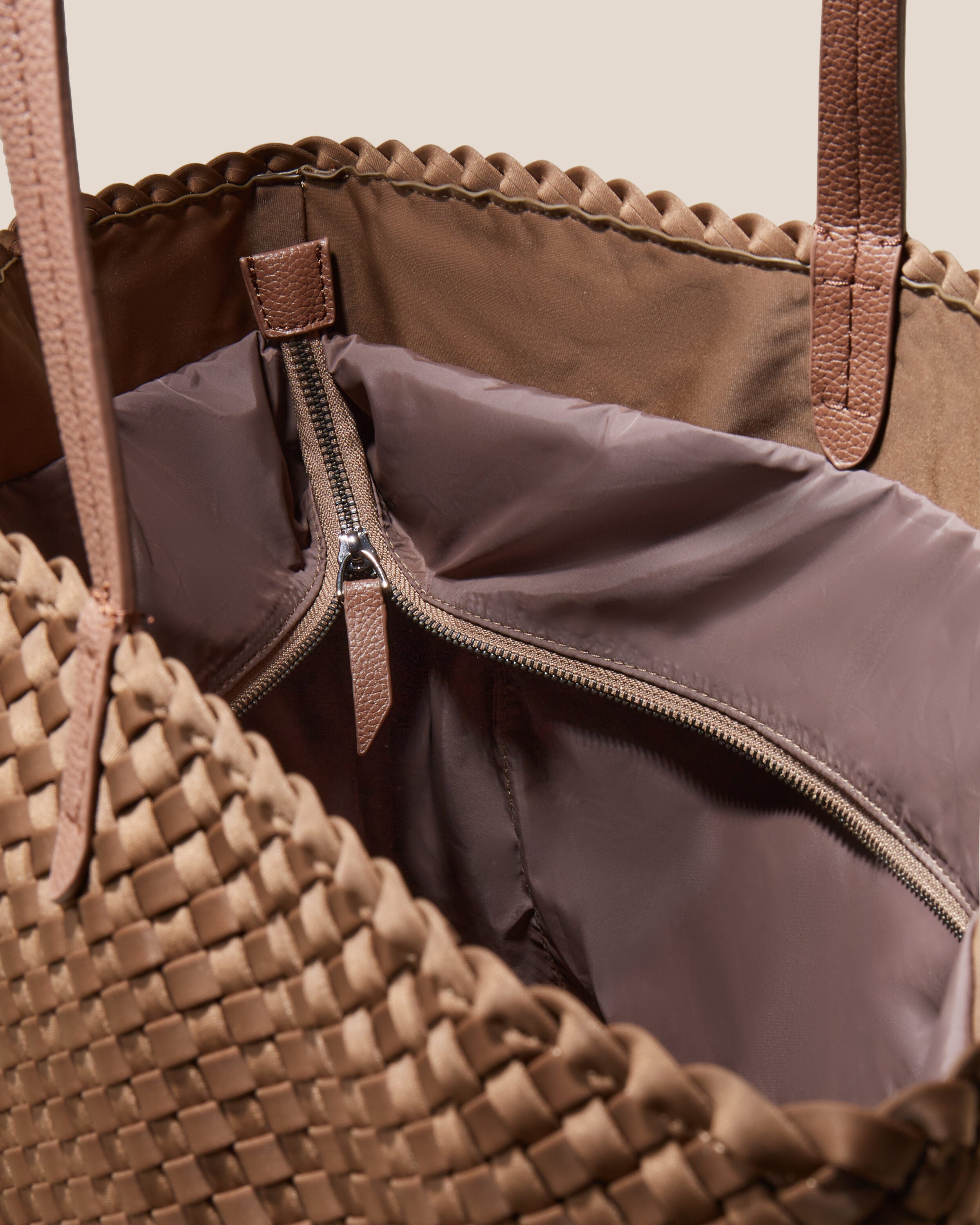 Interior close-up of Jetsetter Tote in Mink showing its top zip closure, interior pockets, and wipe-clean nylon interior.