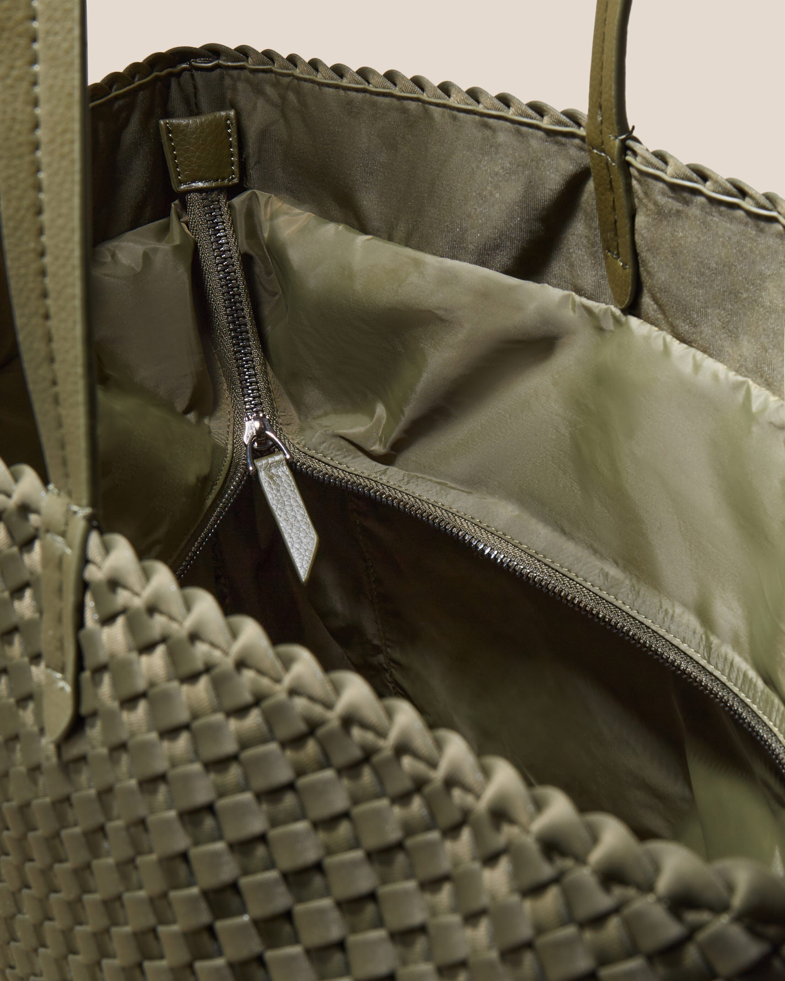 Interior close-up of Jetsetter Tote in Olive showing its top zip closure, interior pockets, and wipe-clean nylon interior.