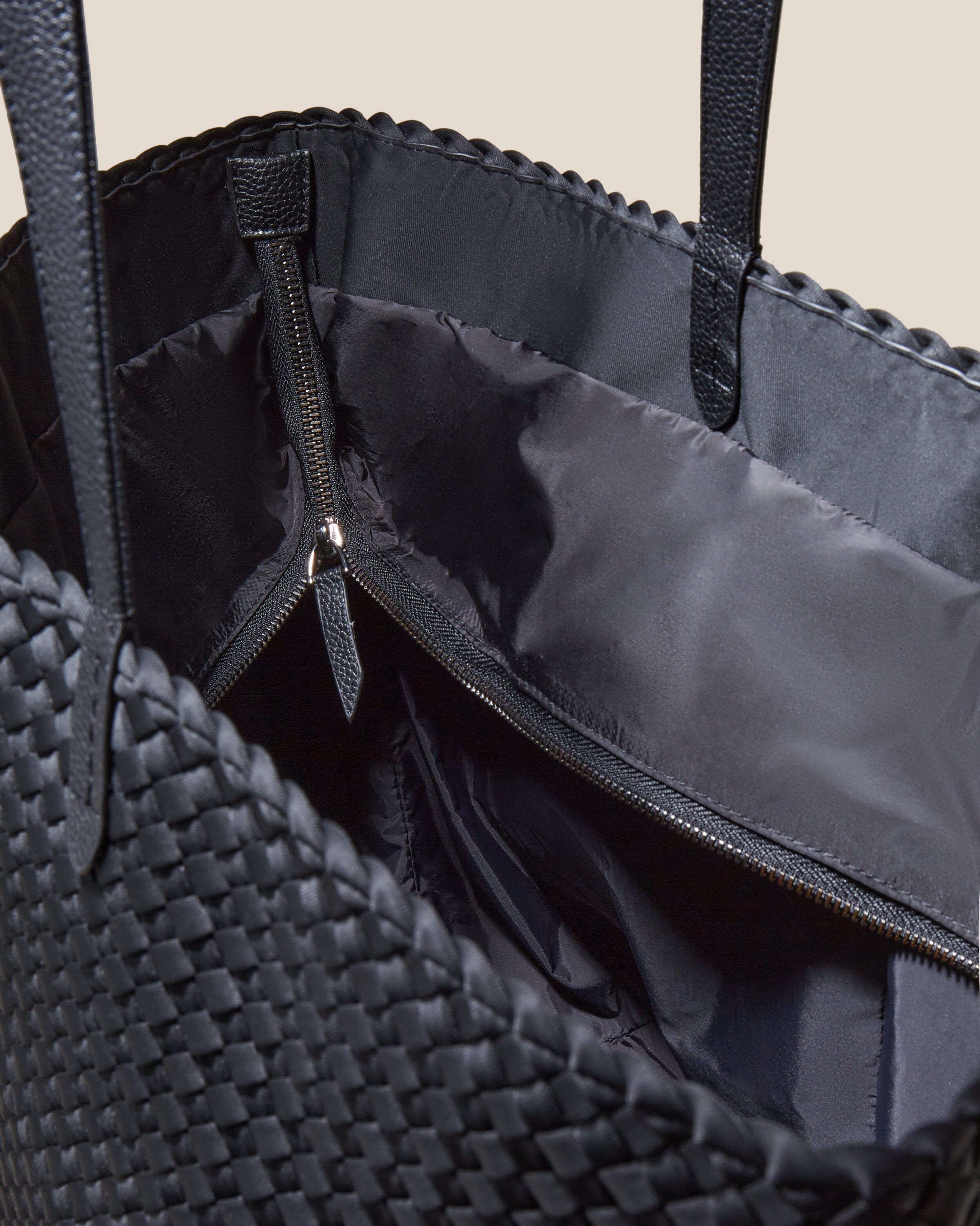 Interior close-up of Jetsetter Tote in Onyx showing its top zip closure, interior pockets, and wipe-clean nylon interior.