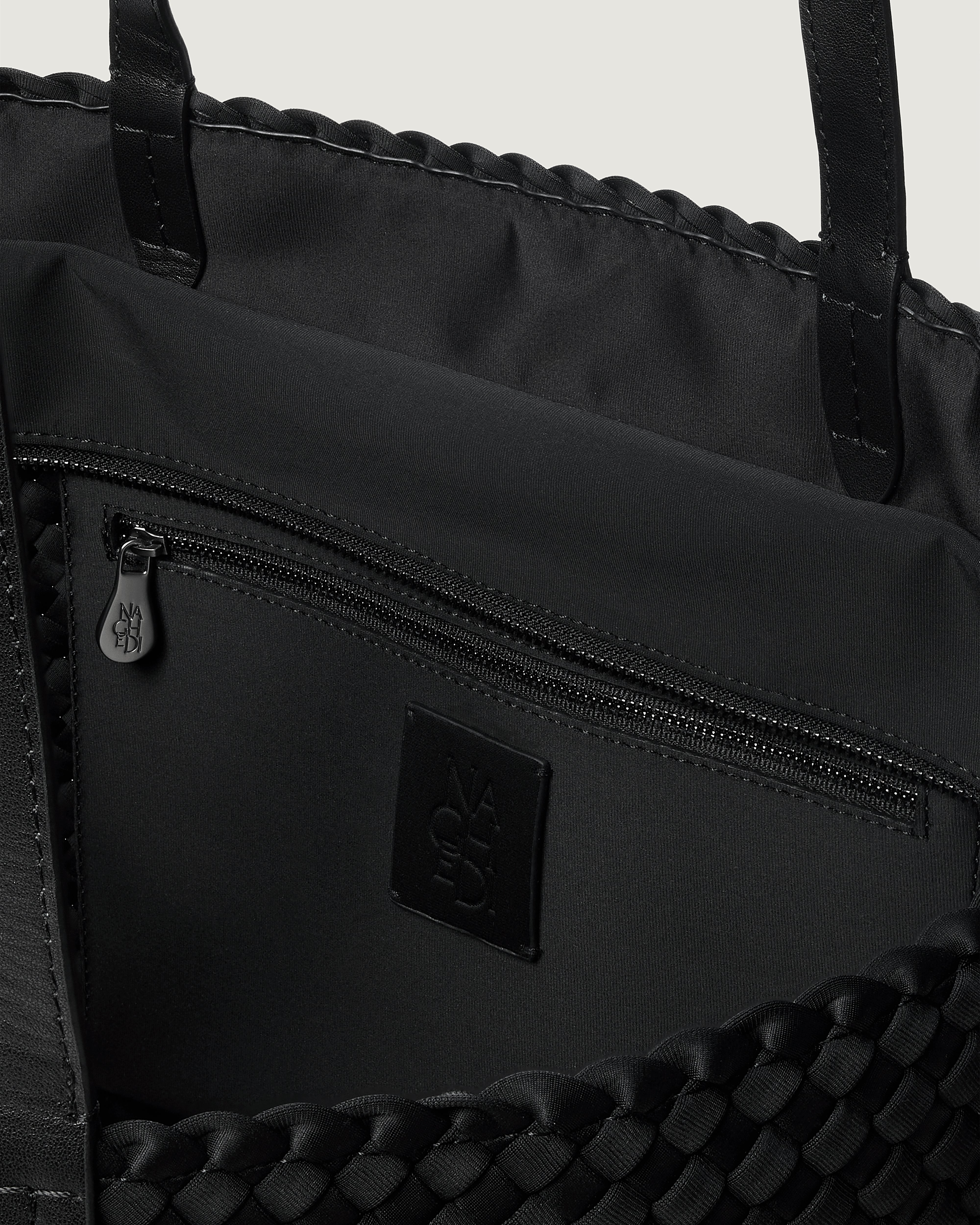 Interior close-up of Jetsetter Tote in Onyx showing its top zip closure, interior pocket, and unlined interior.