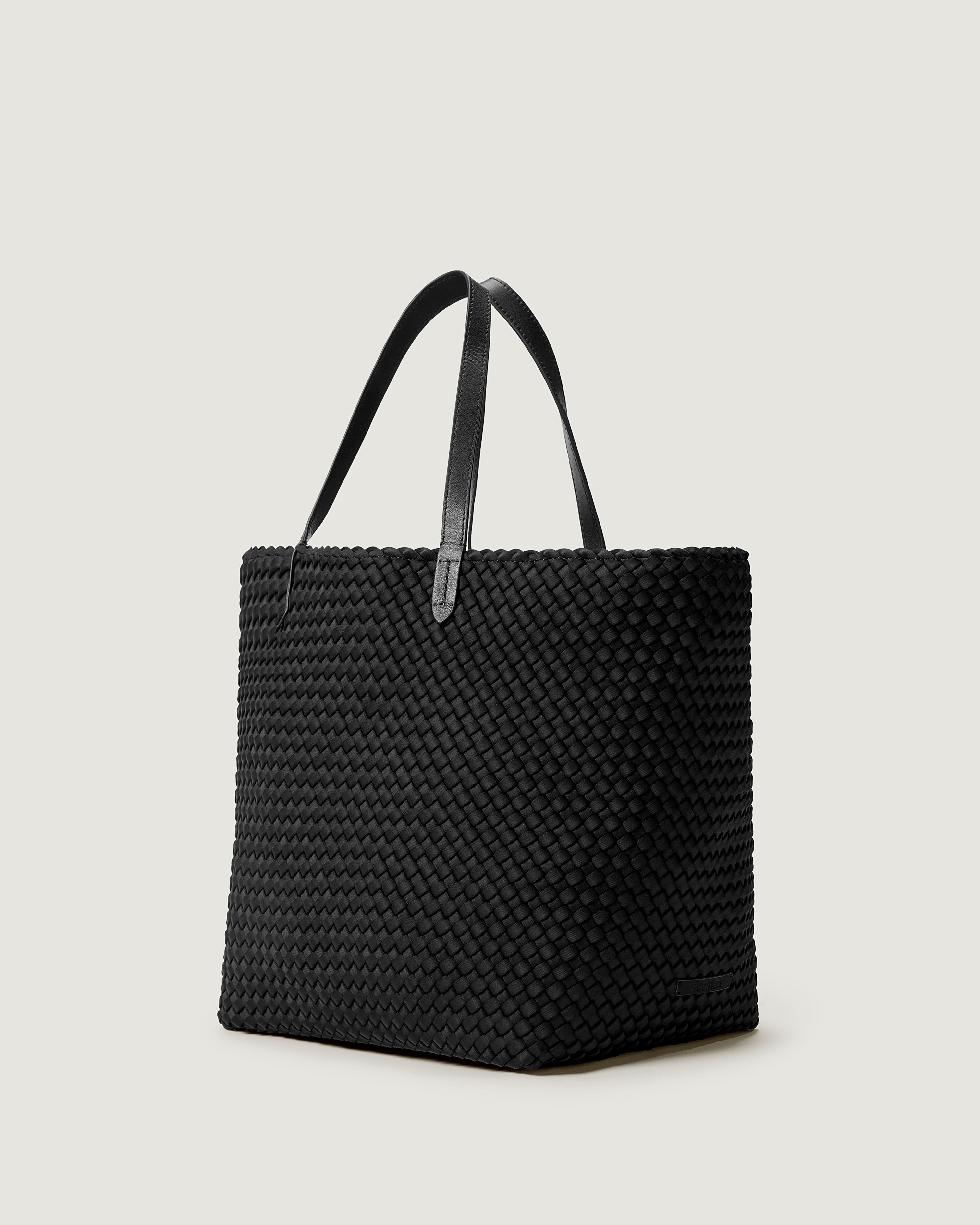 Jetsetter Tote in Onyx shown from a side angle, highlighting its handwoven neoprene construction and top zip closure.