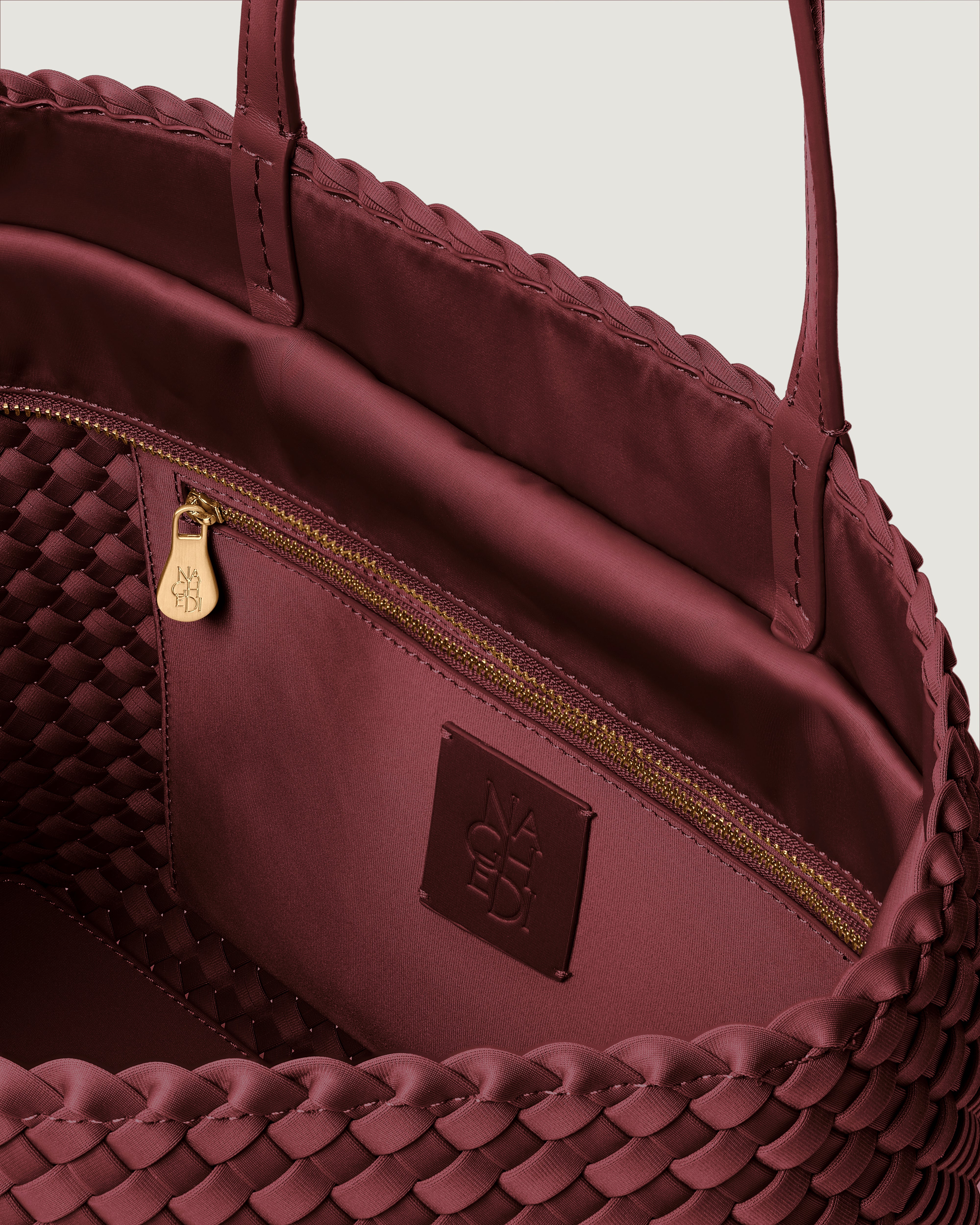 Interior close-up of Jetsetter Tote in Bordeaux showing its top zip closure, interior pocket, and unlined interior.