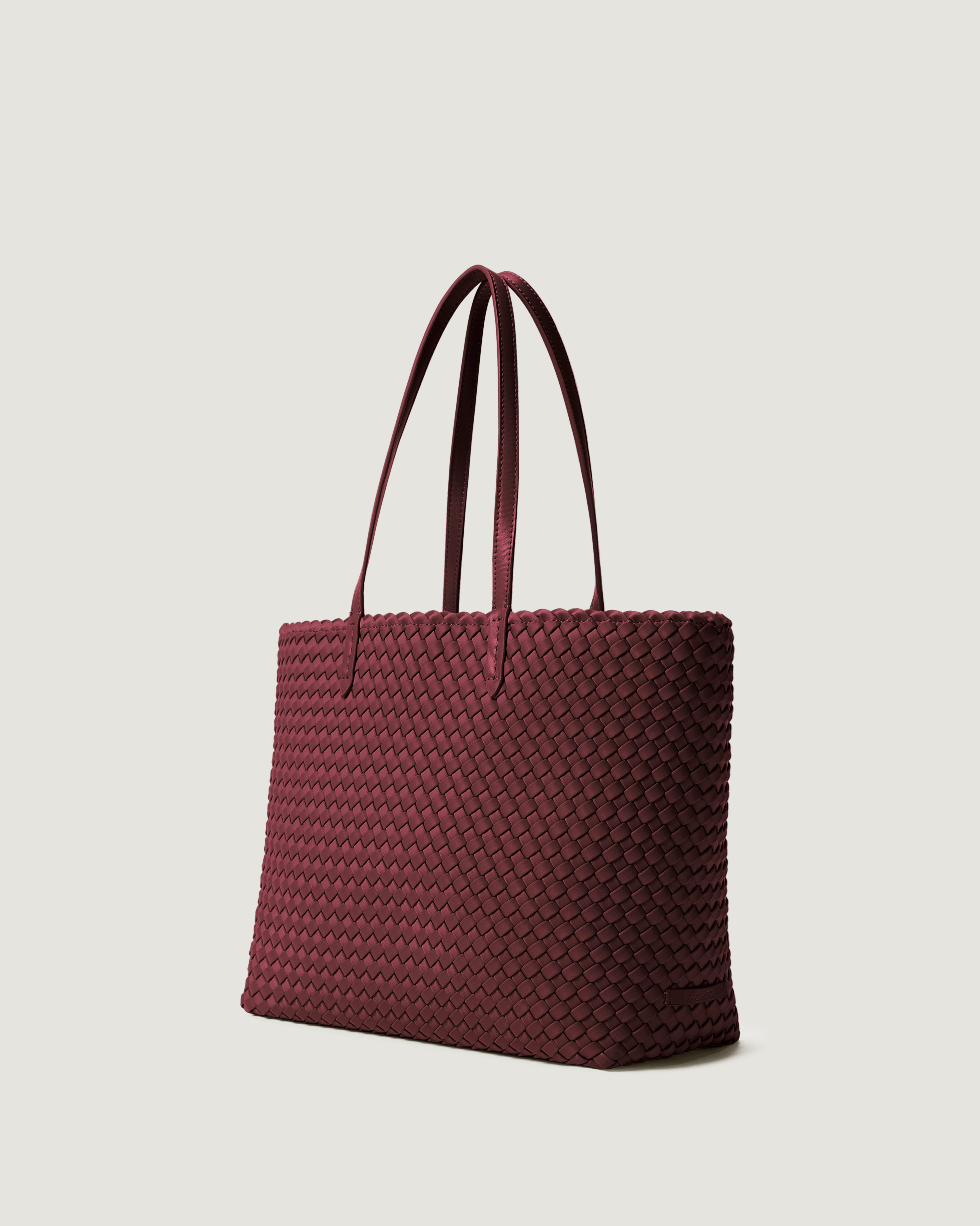 Jetsetter Tote in Bordeaux shown from a side angle, highlighting its handwoven neoprene construction and top zip closure.