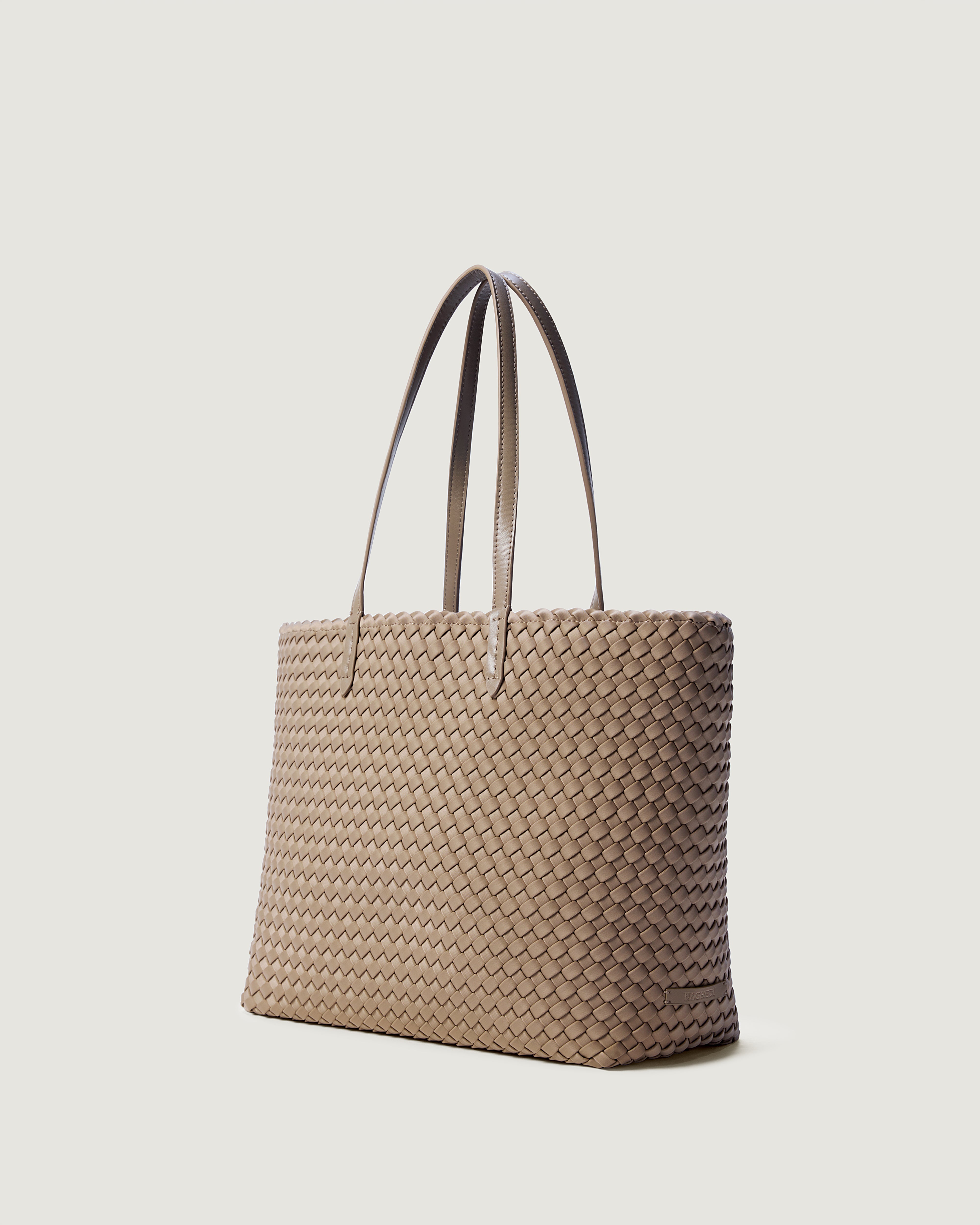 Jetsetter Tote in Cashmere shown from a side angle, highlighting its handwoven neoprene construction and top zip closure.