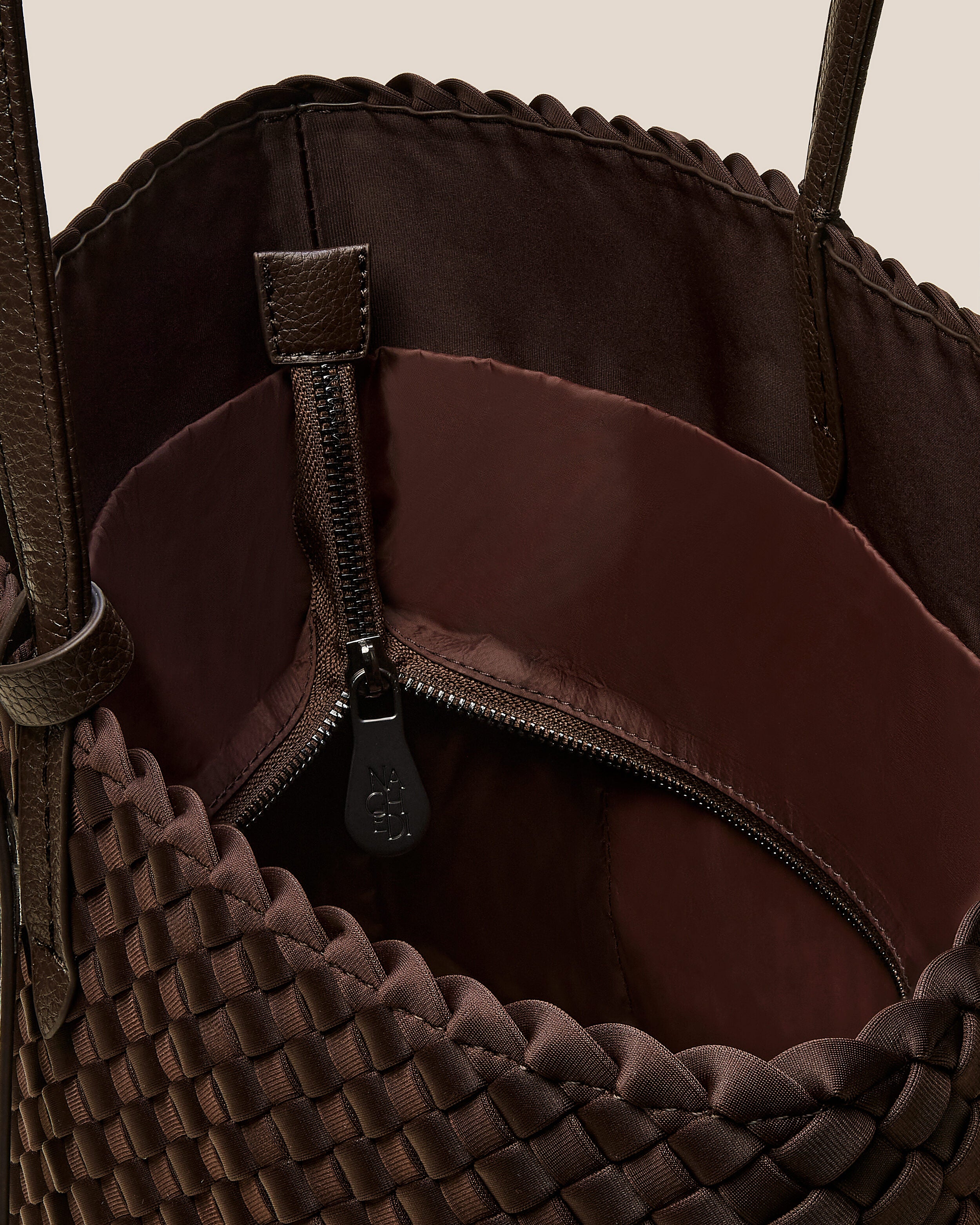 Interior close-up of Jetsetter Tote in Chocolate showing its top zip closure, interior pockets, and wipe-clean nylon interior.