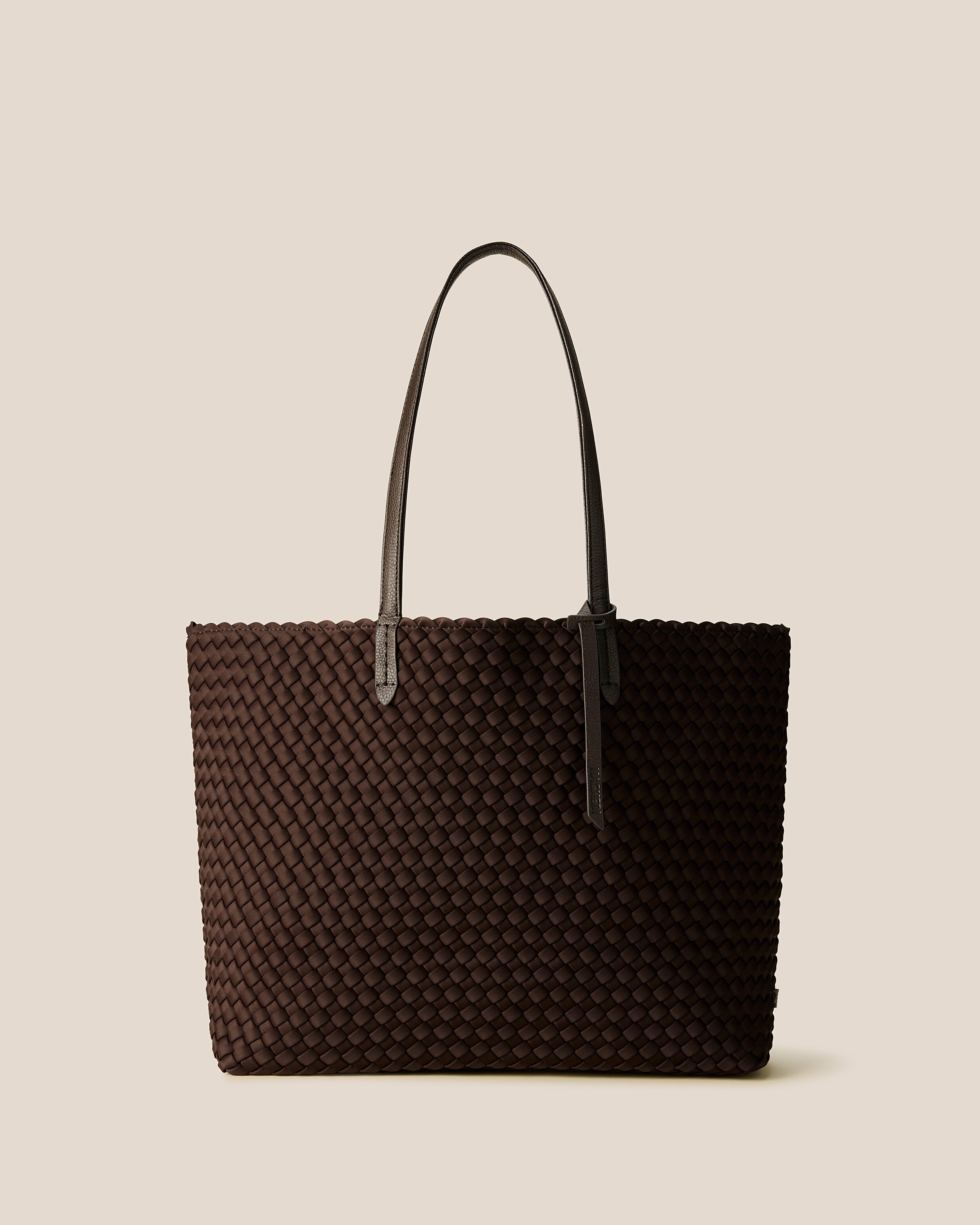 Jetsetter Tote in Chocolate, a dark chocolate brown tone, in handwoven neoprene, featuring a top zip closure, and vegan leather handles.