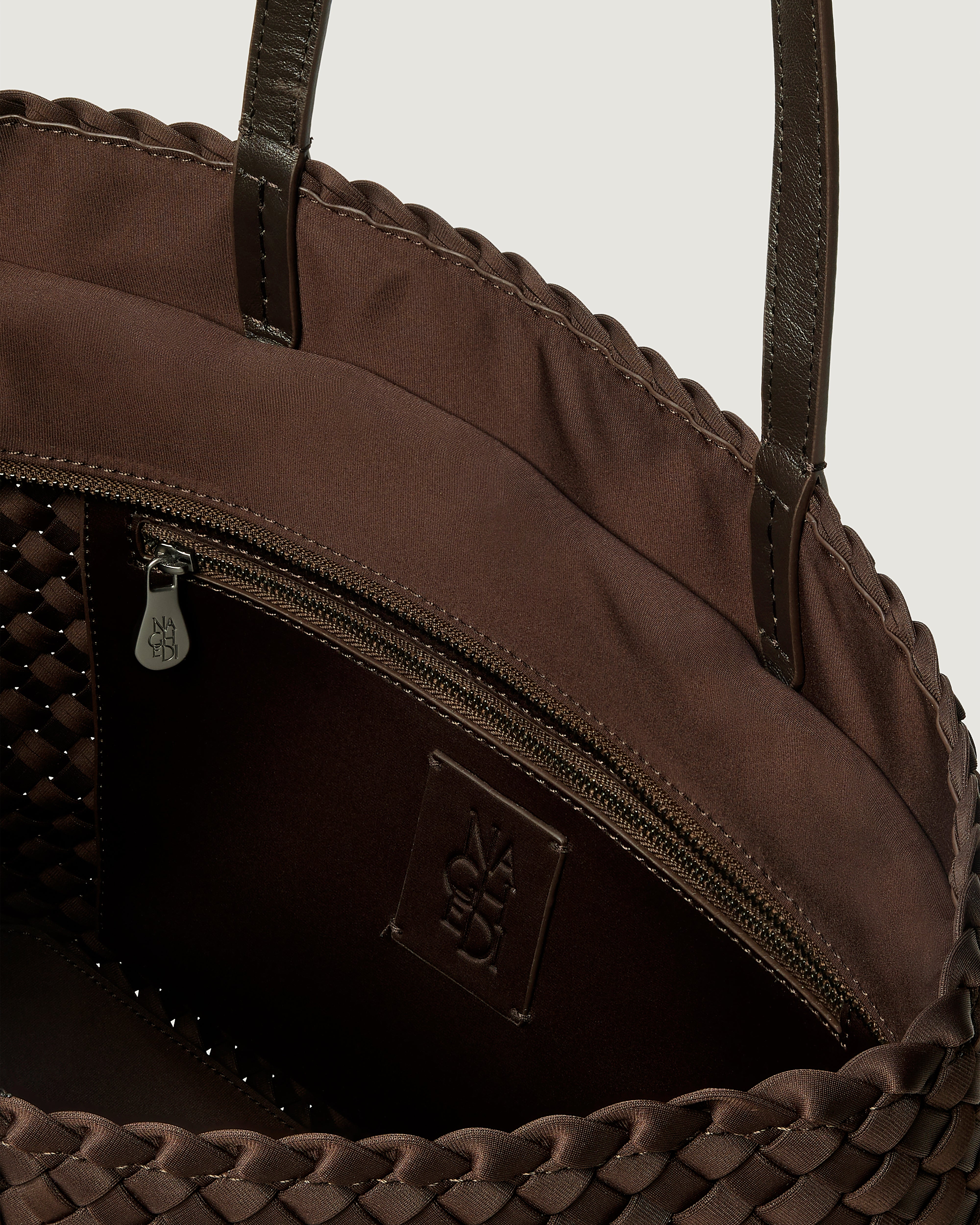 Interior close-up of Jetsetter Tote in Chocolate showing its top zip closure, interior pocket, and unlined interior.