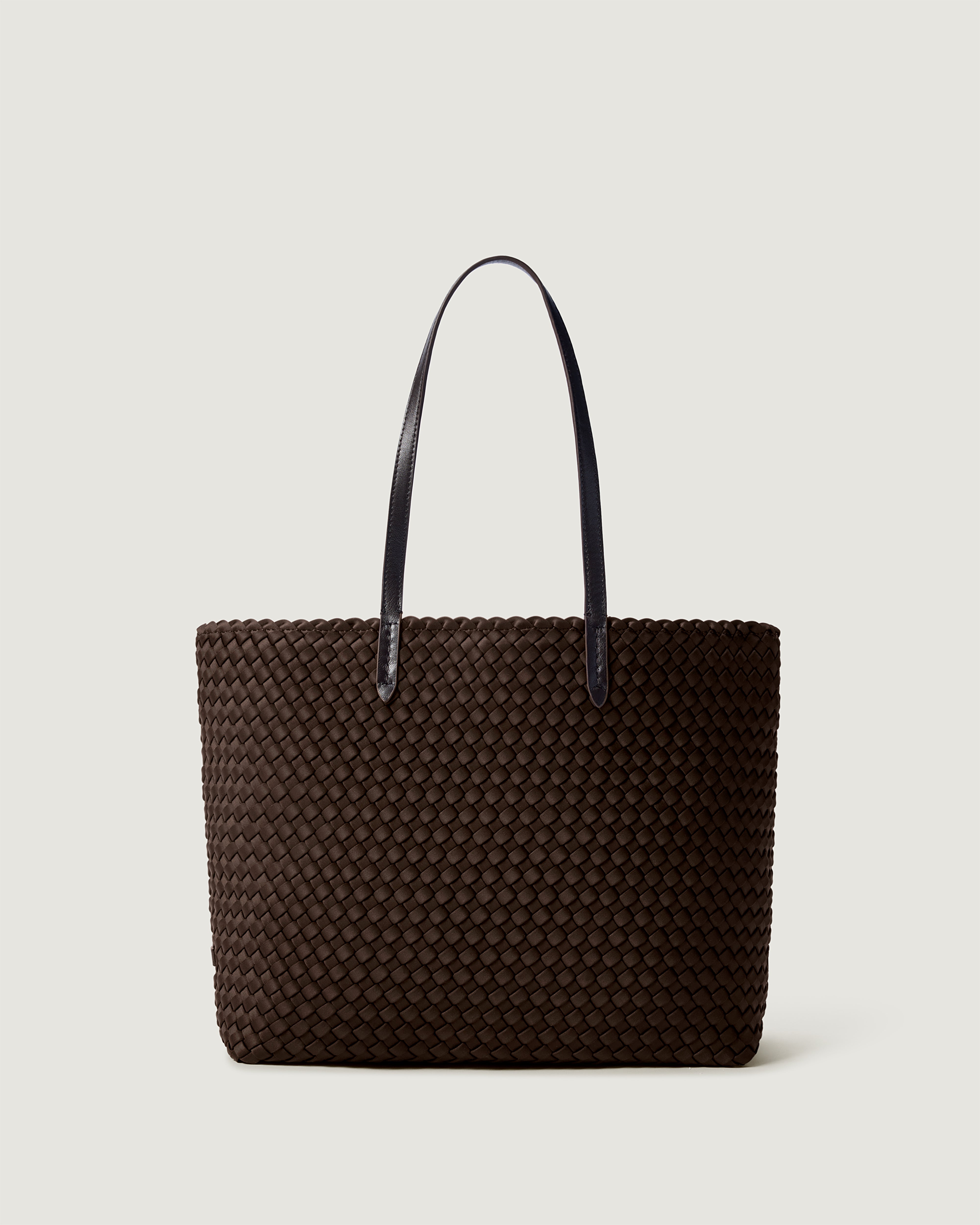 Jetsetter Tote in Chocolate, a dark chocolate brown tone, in handwoven neoprene, featuring a top zip closure, and leather handles.