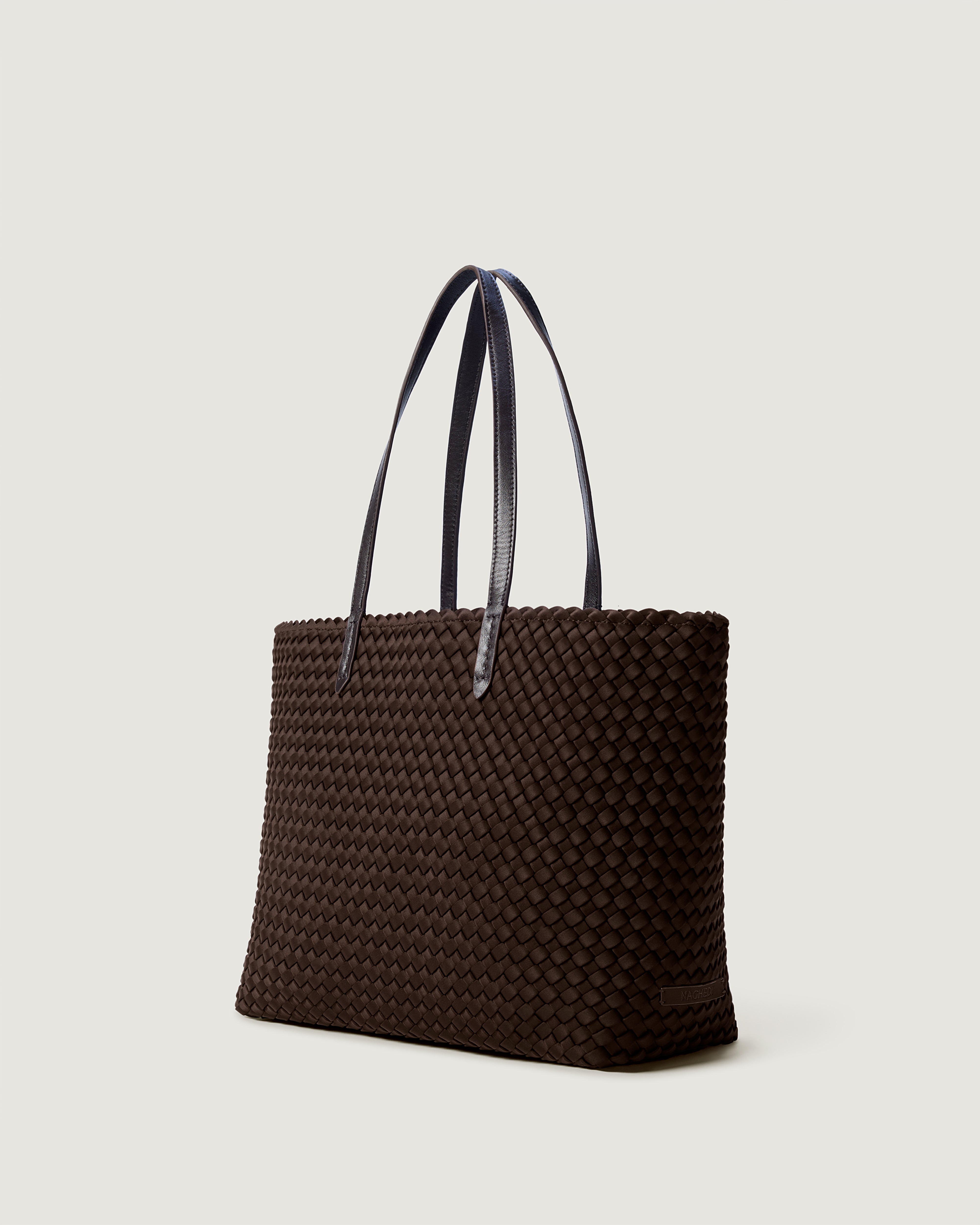 Jetsetter Tote in Chocolate shown from a side angle, highlighting its handwoven neoprene construction and top zip closure.