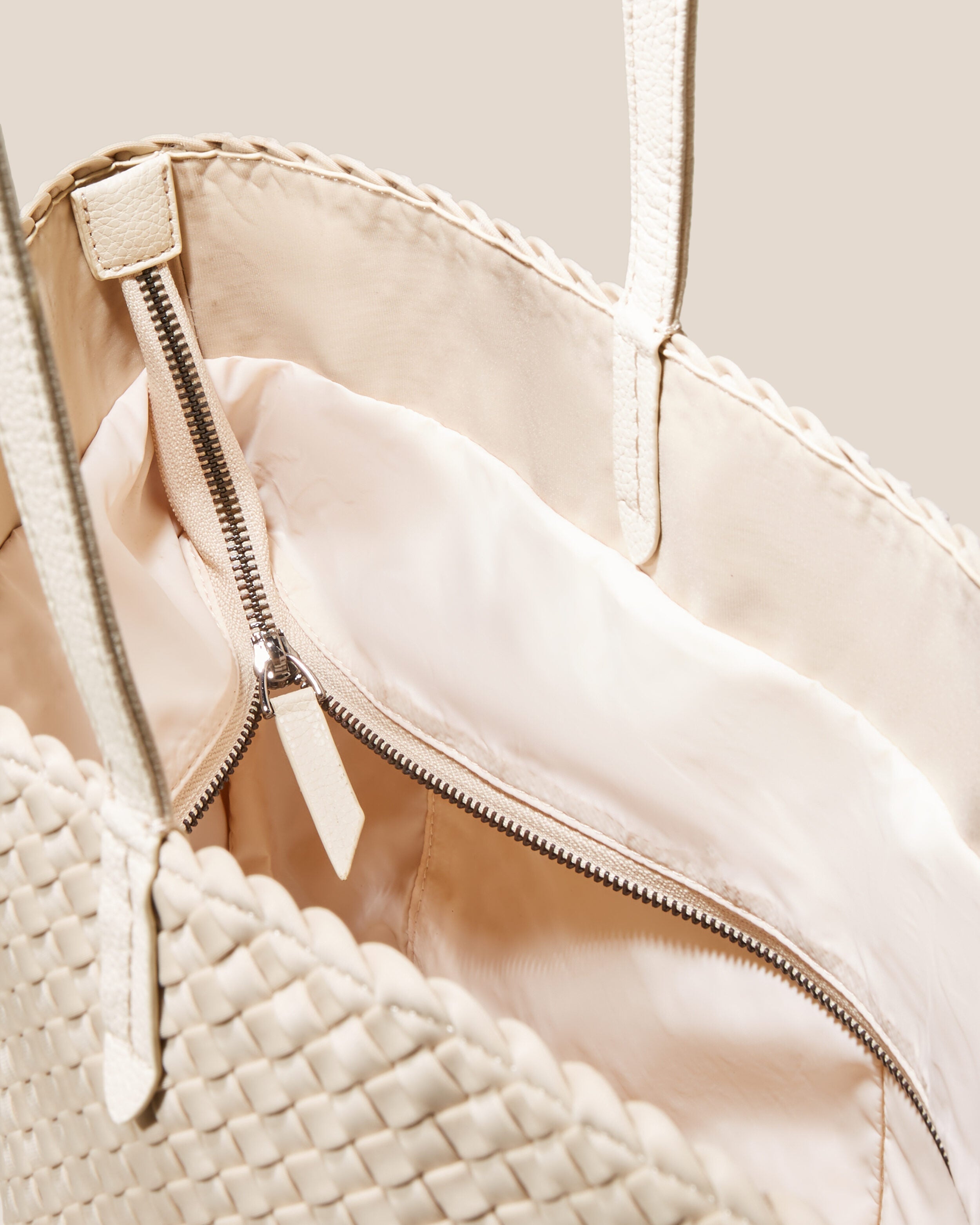 Interior close-up of Jetsetter Tote in Ecru showing its top zip closure, interior pockets, and wipe-clean nylon interior.