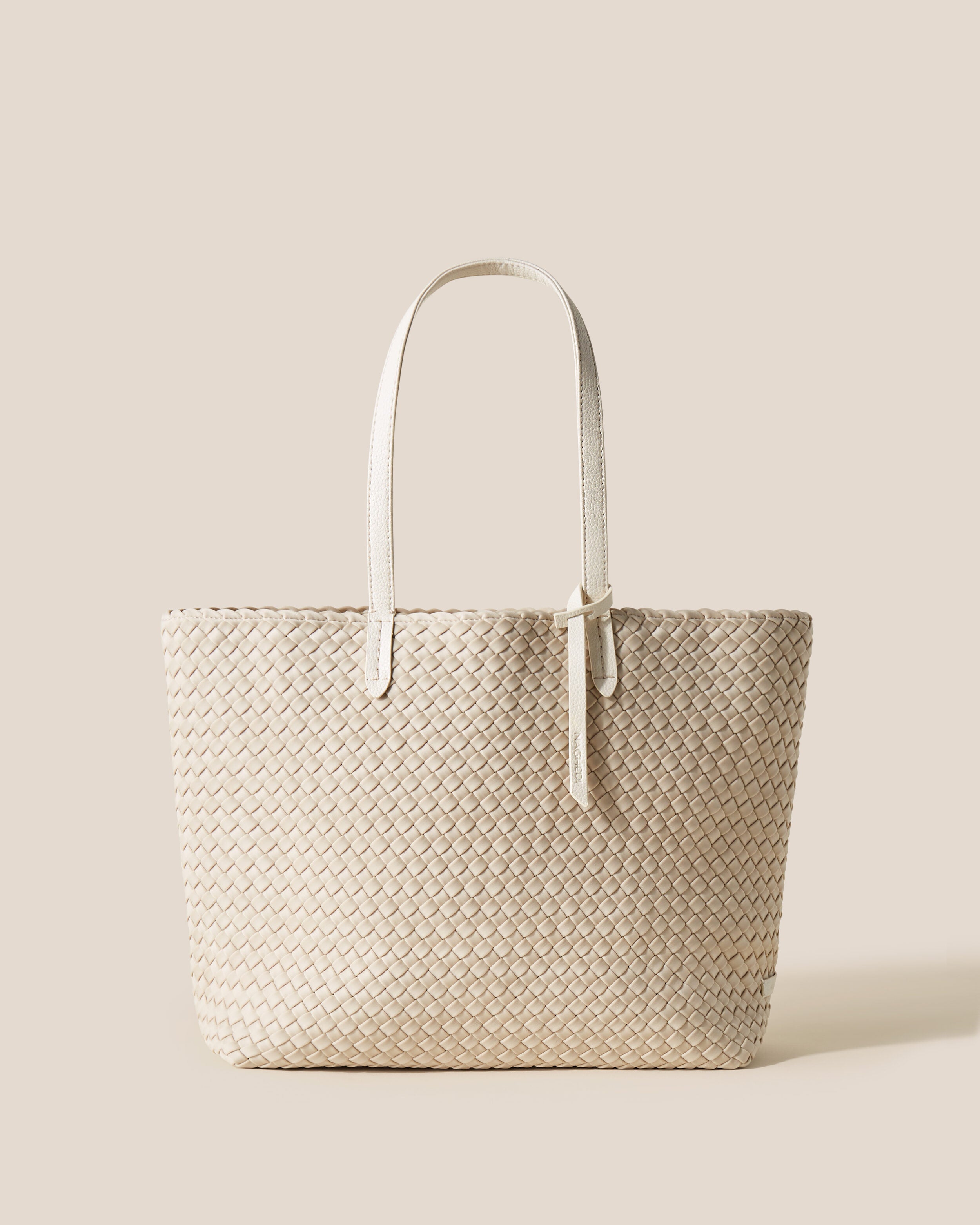 Jetsetter Tote in Ecru, a cream tone, in handwoven neoprene, featuring a top zip closure, and vegan leather handles.