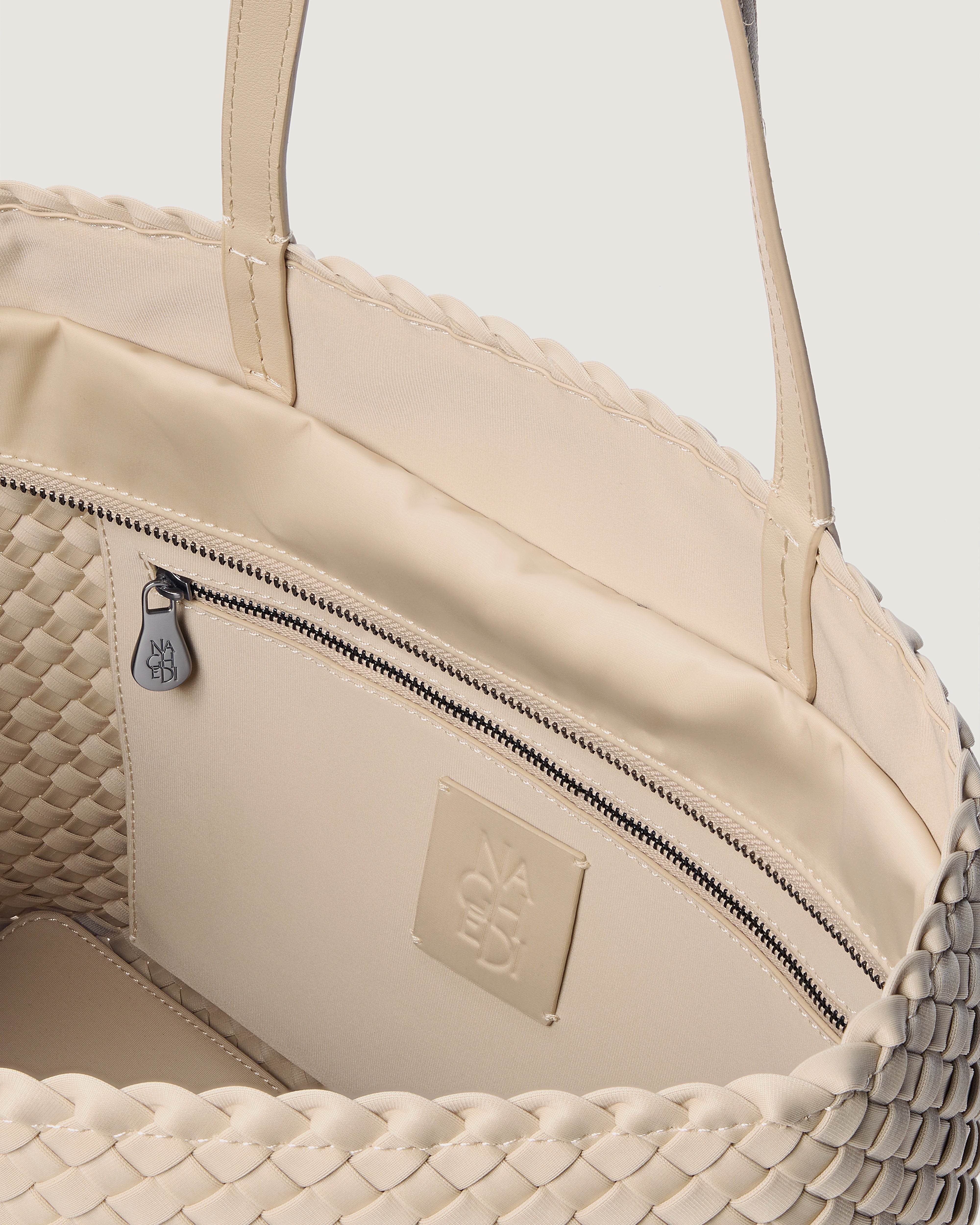 Interior close-up of Jetsetter Tote in Ecru showing its top zip closure, interior pocket, and unlined interior.