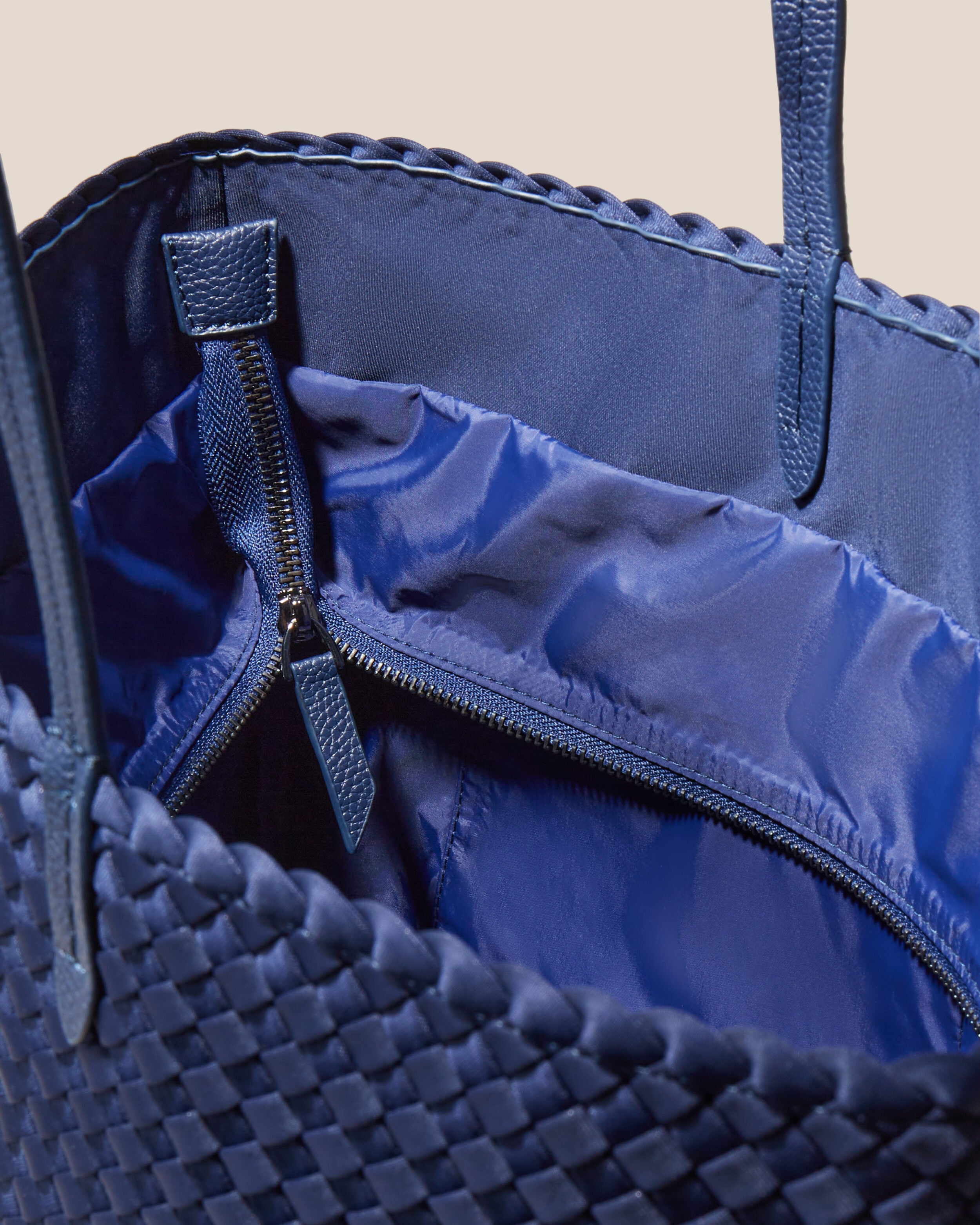 Interior close-up of Jetsetter Tote in Ink Blue showing its top zip closure, interior pockets, and wipe-clean nylon interior.