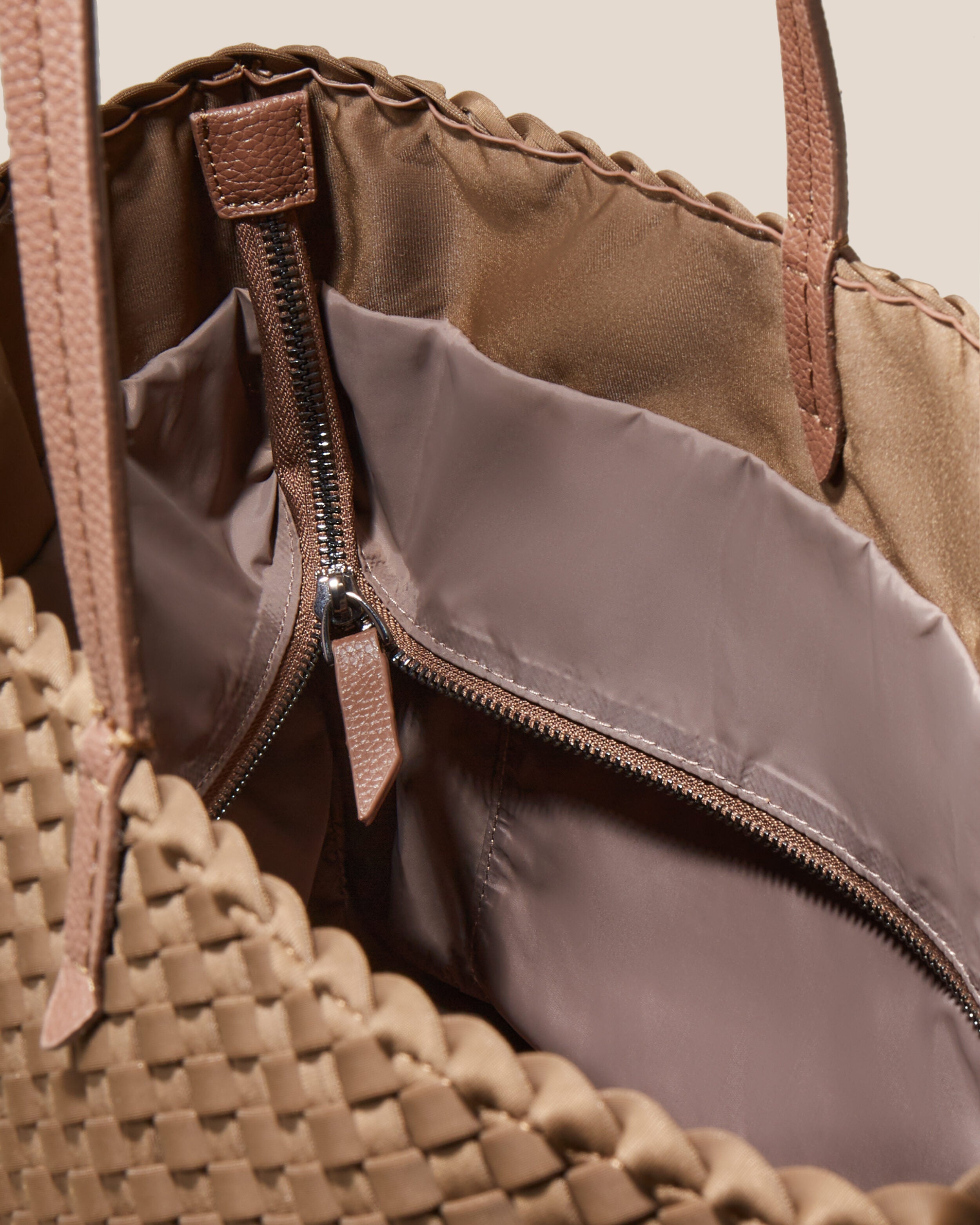 Interior close-up of Jetsetter Tote in Mink showing its top zip closure, interior pockets, and wipe-clean nylon interior.