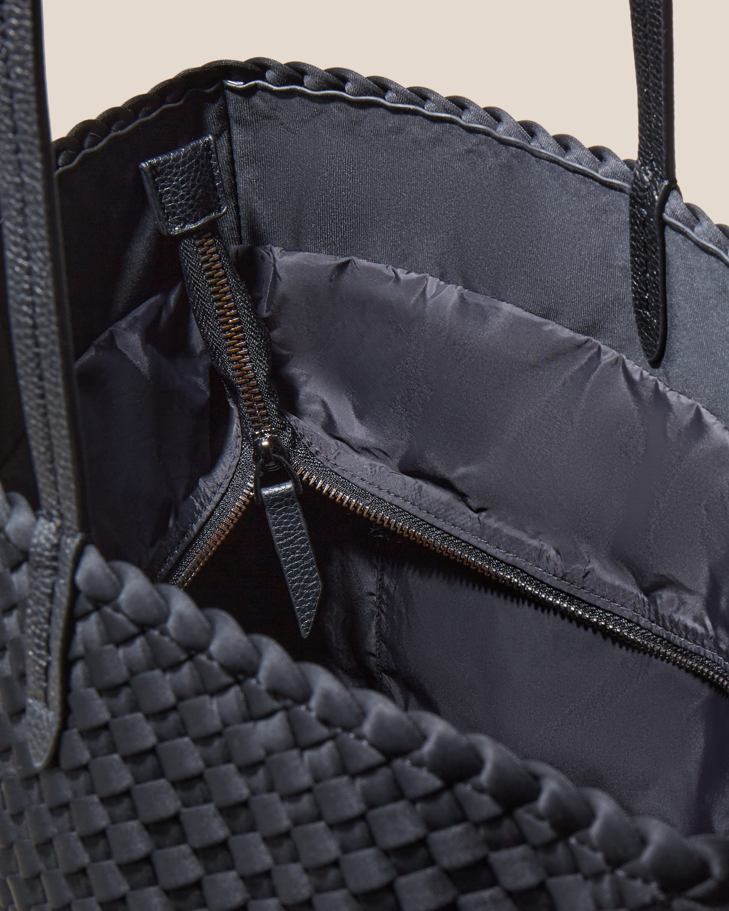 Interior close-up of Jetsetter Tote in Onyx showing its top zip closure, interior pockets, and wipe-clean nylon interior.
